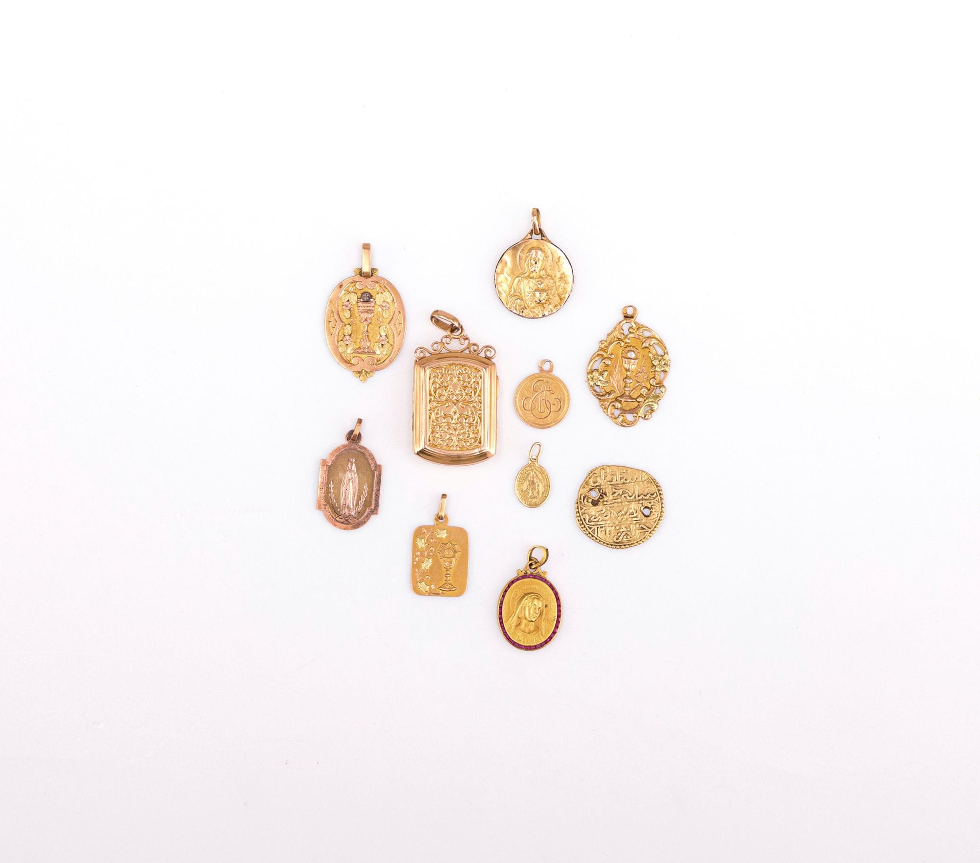 Lot de médailles et pendentifs, en or (18K). Poids brut: 27,6 g
- 6 médailles religieuses.
- 1 médaille religieuse avec tour en pierres rouges. Poids brut: 4,8 g 
- 1 pendentif rectangulaire ouvrant (sans verre).
- 1 pièce étrangère percée  en or (18K)
On joint une médaille religieuse en métal 
