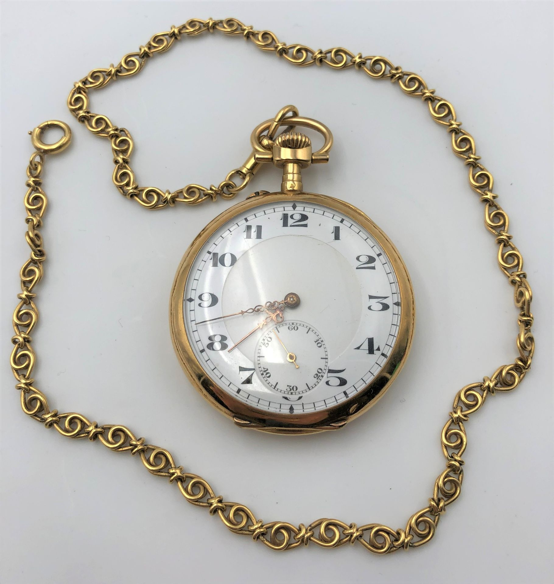 Montre de poche en or (18K) avec sa chaine en or (18K). Poids brut : 95 g
(Montre : 70,3 g - Chaine : 24,7 g)