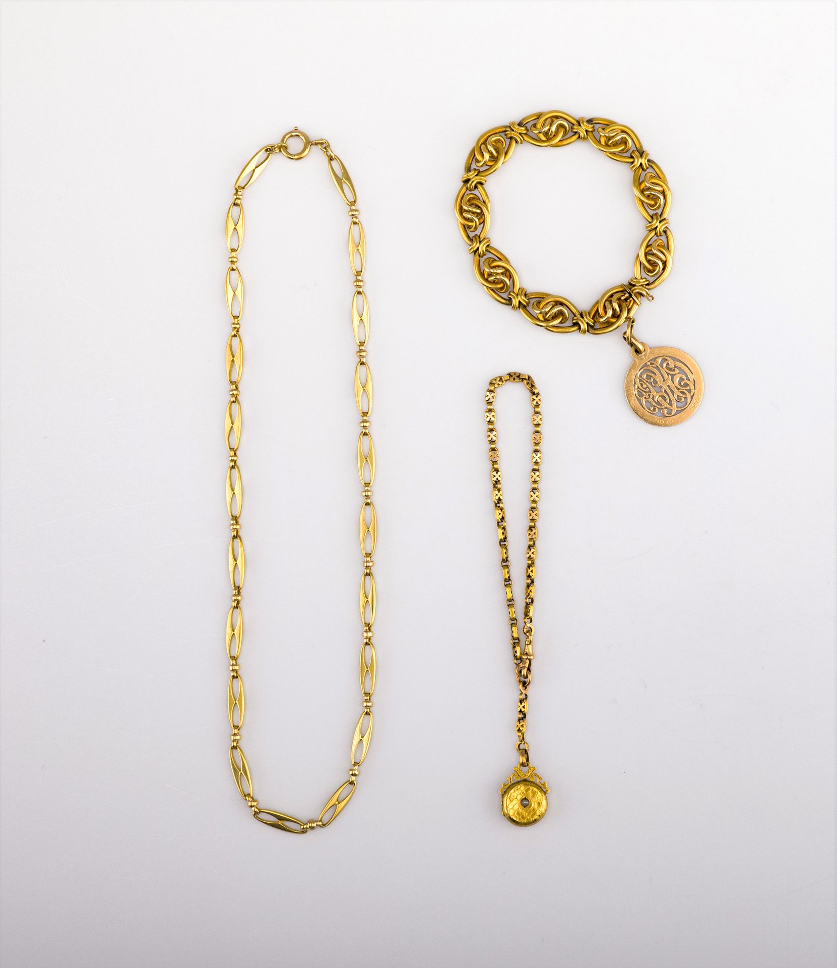 Lot de bijoux en or (18K). Poids brut : 42,8 g
- 1 collier souple à maillons ovales ajourés. Poids : 32 g 
- 1 chaine de montre et pendentif (cadre ouvrant avec verre). Poids brut: 10,8 g
