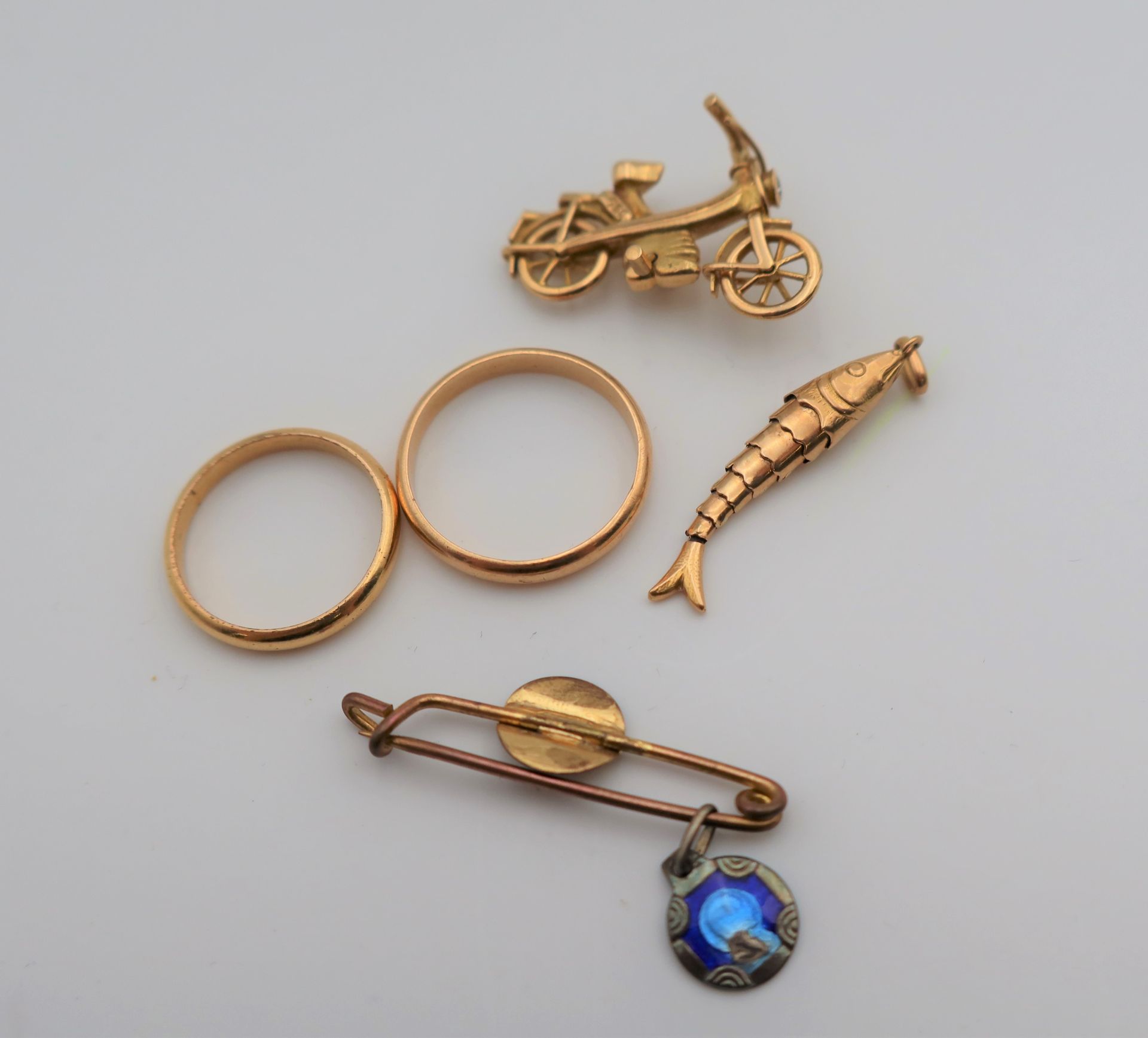 Lot de bijoux en or (18K). Poids brut: 10,8 g
(1 broche vélo, 1 pendentif poisson, 2 alliances)