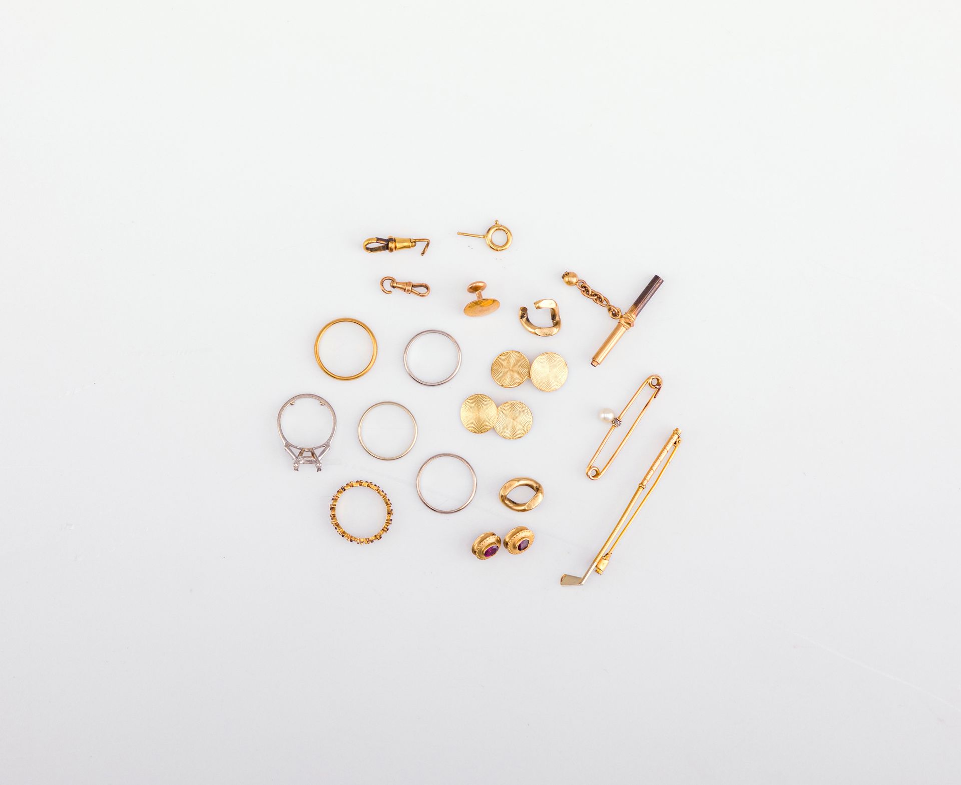 Lot de bijoux en or (18K) et platine. Poids brut total : 43,4 g
- 3 alliances (dont 1 en or blanc et 1 dite "américaine"), 2 broches (dont 1 barette avec perle), 1 paire de boutons de manchette, 1 bouton de col, divers fermoires, 2 éléments avec pierres serties, etc.Poids brut : 30,1 g 
- 2 anneaux de gourmette en or (12K). poids: 4,9 g 
- 1 monture de bague et 2 alliances, en platine. Poids brut : 8,4 g

