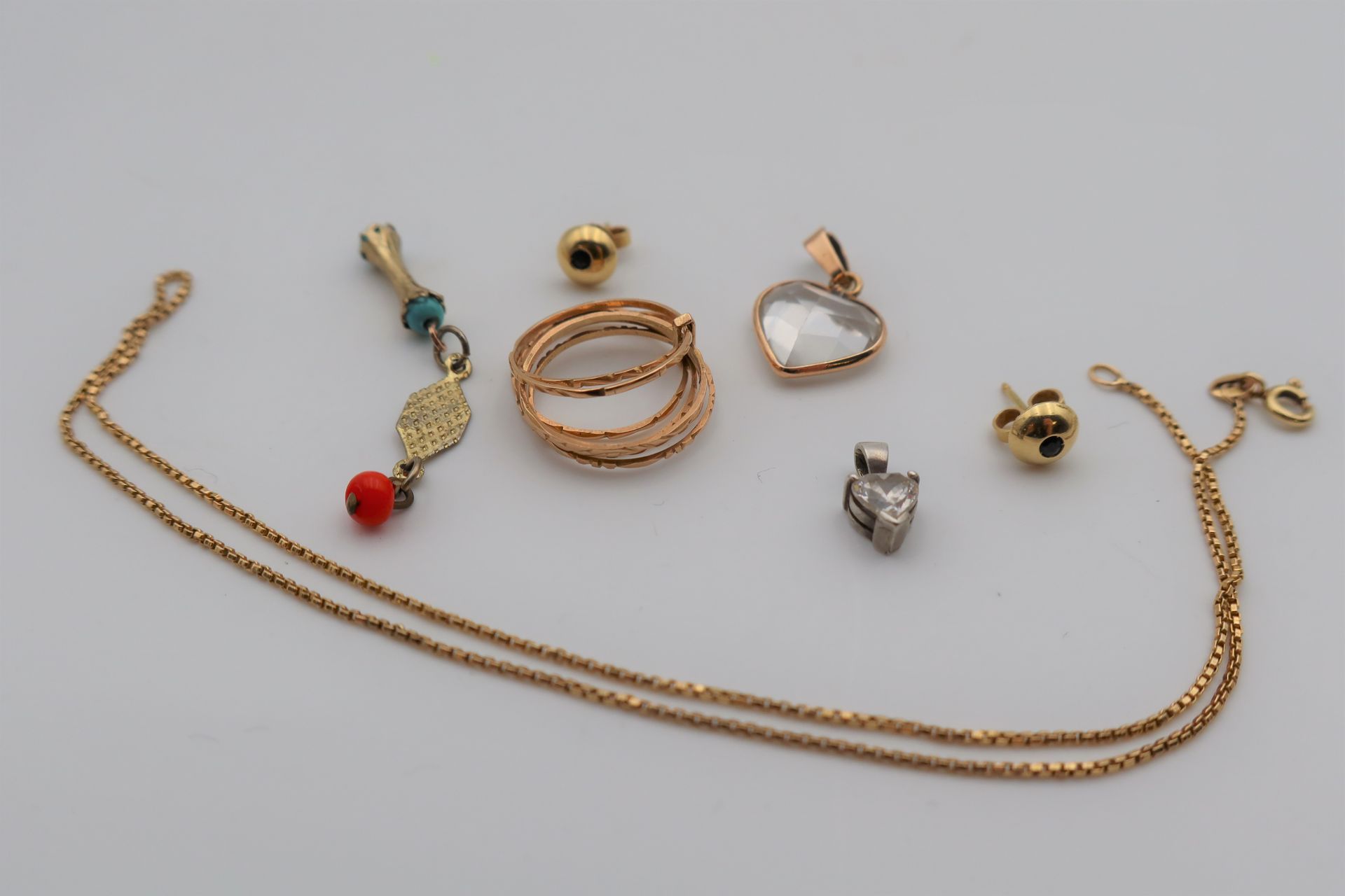Petit lot de bijoux en or (18K), argent et pierres. Poids brut: 9,5 g
- 1 chaine en or et (2,8 g) et pendentif coeur. Poids brut: 4,7 g
- 1 bague 7 anneaux. Poids: 2, 8 g
- 1 paire de boucle d'oreilles. Poids brut: 2,1 g
- 1 pendentif coeur serti en argent. Poids brut: 0,8 g