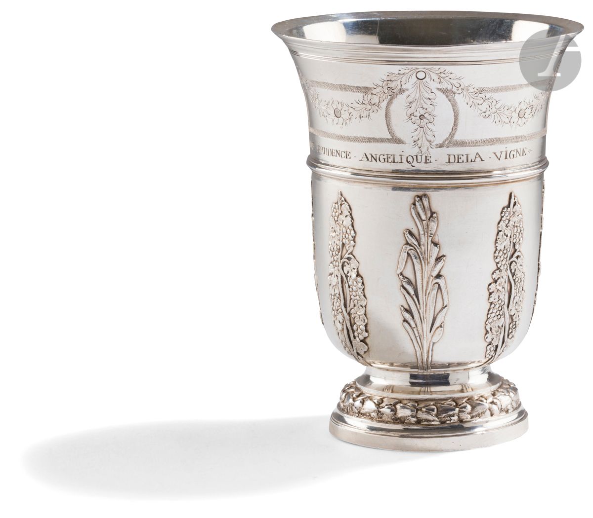 PARIS 1774 
Timbale tulipe en argent à appliques. Le piédouche est repoussé d’une tresse de lauriers. Le corps est rehaussé d’appliques aux deux tiers alternant roseaux et treille de vigne délimitées par un jonc de filets . Sous le col est gravée une guirlande fleurie et chutes de fleurs sur un fond amati d’encadrements géométriques encadrant des médaillons, dont l’un reçoit un chiffre de lettres entrelacées. Au-dessus du jonc est gravé le patronyme : REINE PRUDENCE ANGELIQUE DELA VIGNE
Maître orfèvre : Jacques FAMECHON, reçu en 1770
Poids : 205 g - hauteur : 12,3 cm
