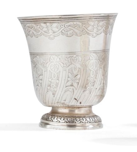 PARIS 1756 - 1757
Timbale tulipe en argent reposant sur un piédouche repoussé d’oves et d’entrelacs. Le corps est gravé sur deux registres, séparés par un filet, d’appliques obliques sur fond amati, figurant des lambrequins de fleurs et dans la partie haute d’entrelacs fleuris sur fond amati de même.
Maître orfèvre : illisible
Poids : 120 g - hauteur : 9,5 cm
État : à redresser