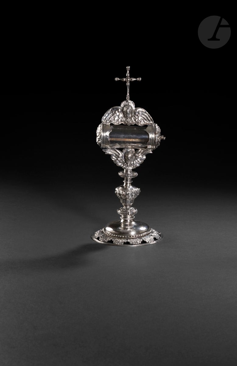 
FRANCE PROVINCE XVIIe SIÈCLE



Reliquaire en argent repoussé et verre. Le piédouche, circulaire, est ajouré de feuilles d’acanthe et d’un rang de perles. Le nœud du fût est orné de trois têtes d’angelots ailés surmontant des feuilles lancéolées encadrés de deux rangs de spirales ajourées. Le porte-relique est supporté à la base par une tête d’angelot ailé double face en rappel sur la partie supérieure sommée d’une croix. 



Maître orfèvre : H M une fleur de lys couronnée, différent une fleur



Poids brut : 470 g - hauteur : 32,5 cm



État : support de l’ampoule en verre partiellement dessoudé, verre changé et manque à l’extrémité fixe du reliquaire. 
TOUT PETIT MANQUE SOUS LE SUPPORT EN VERRE.