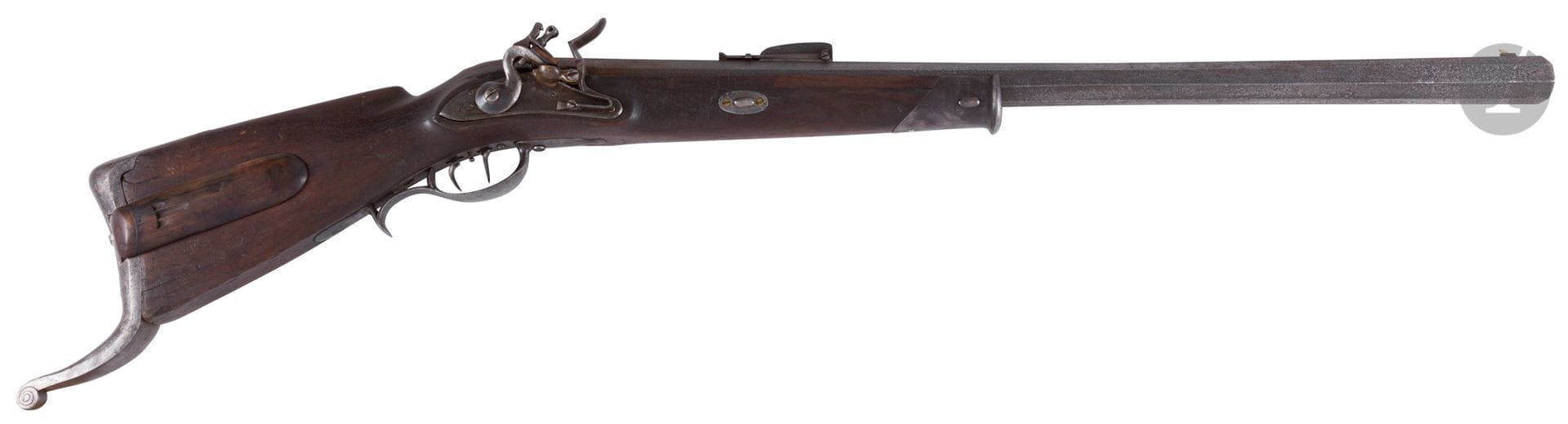 Strong rifle of shooting, with flint. 

Barrel with sides with rise, striped, punched with the thunder. Flat body lock and round body gooseneck hammer (repaired in the past). Double trigger stecher. Trim and important iron fang butt plate. Mounting (small notch) and stick with cheek in drowning, with posterior drawer. 

Length of the barrel: 91cm Overall length: 128 cm

E.M. Late 18th, early 19th century.
