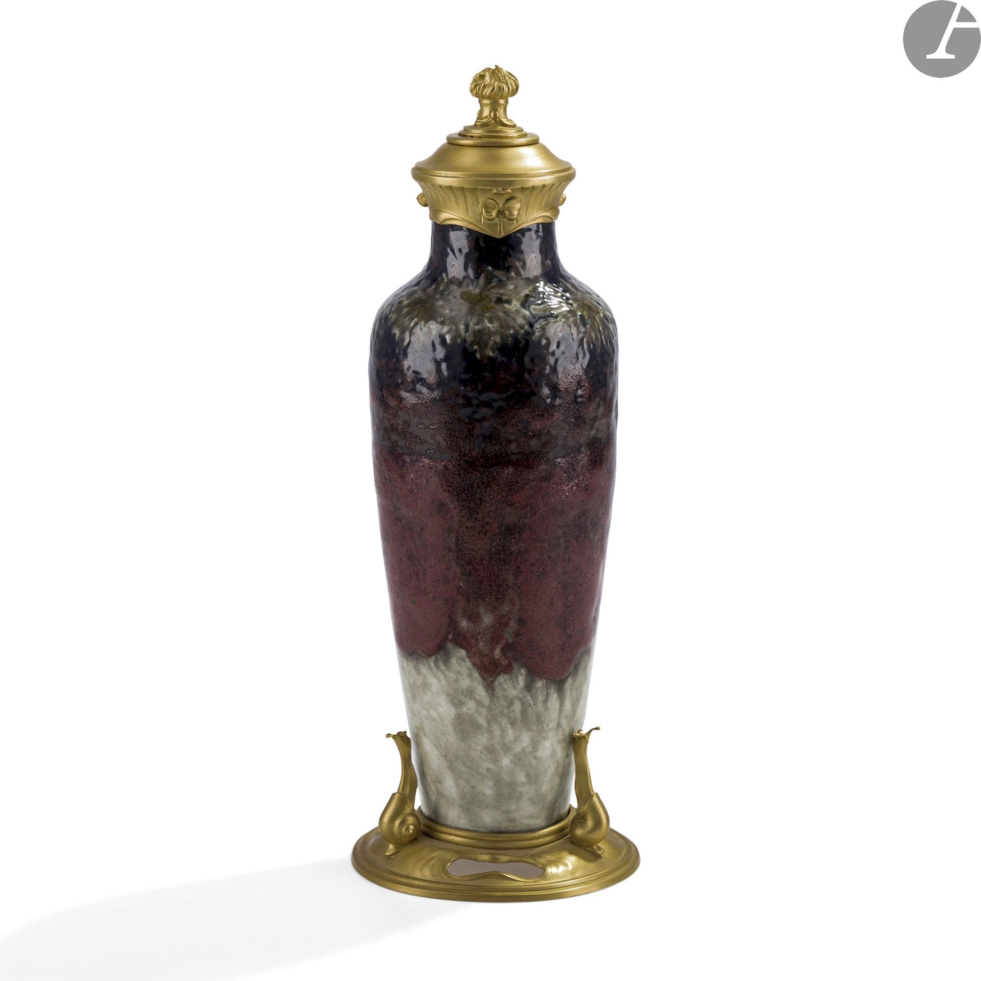 ALBERT DAMMOUSE (1848-1926) CÉRAMISTE À SÈVRES & CARDEILHAC MAÎTRE ORFÈVRE À PARIS
Dahlia, trèfles, escargots et pot à feu
Haut vase balustre monté d’origine. Épreuve en céramique émaillée polychrome au décor de dahlias en frise tournante sur l’épaulement. La base en métal (re)doré aux motifs de gastéropodes, le bouchon, également en métal (re)doré, sommé d’un pot à feu. Les dorures refaites. Monogrammé A. D. et situé Sèvres au revers du vase en céramique (visible un fois démonté). H. 29 cm

À noter :
Un vase de Taxile Doat, présentant une base (aux motifs de gastéropodes) identique à notre vase et portant le cachet Cardeilhac Paris D235, est conservé au Detroit Institute of Arts, USA sous le numéro d’inventaire 2010.11.