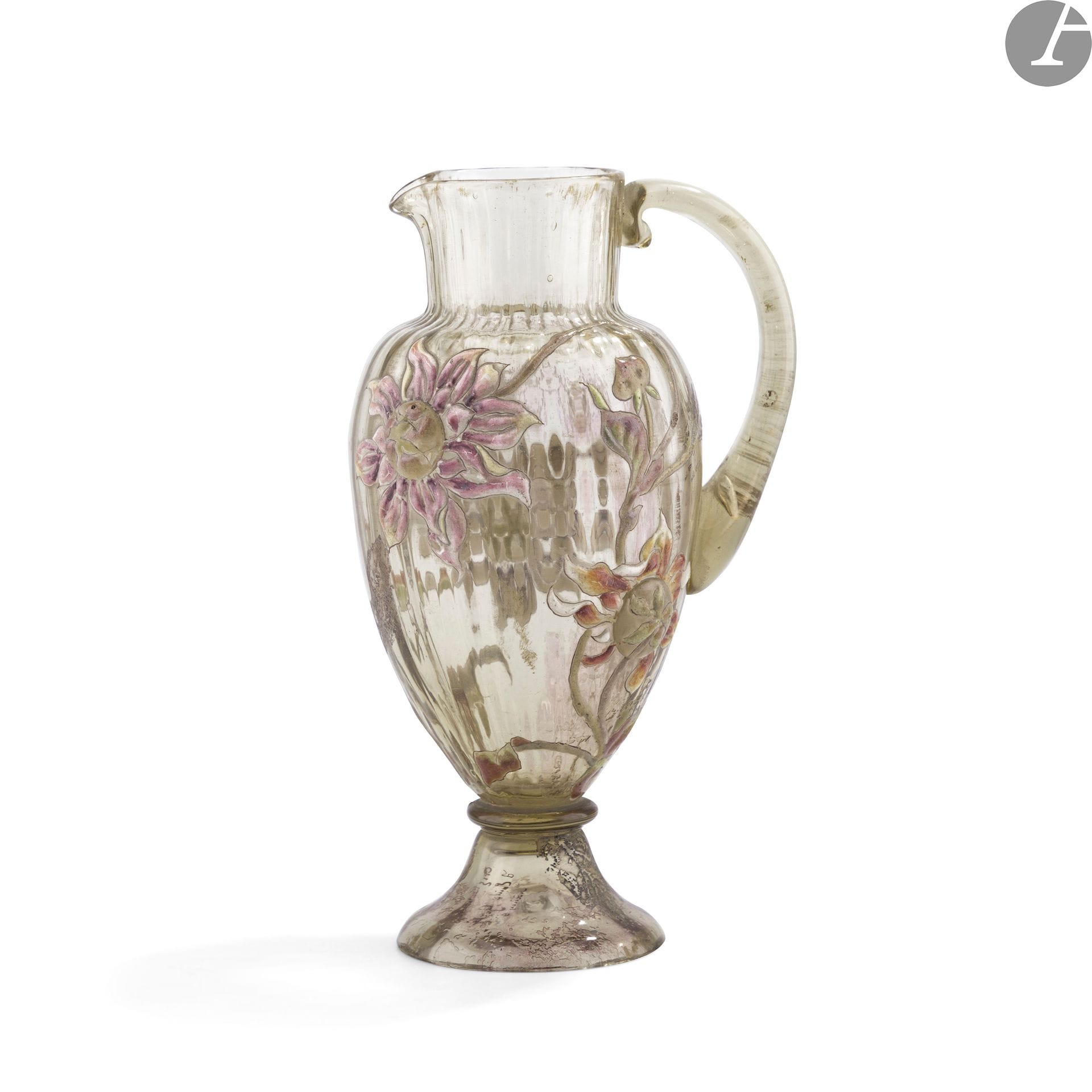ÉMILE GALLÉ (1846-1904)
Dahlias
Verseuse balustre et côtelée sur piédouche ; l’anse détachée modelée et collée à chaud. Épreuve en verre fumé brun au décor, d’une part, dégagé à l’acide et, d’autre part, réalisé aux émaux polychromes et à l’or au four. Les cœurs des fleurs figurés par des cabochons collés à chaud et rehaussés aux émaux polychromes. Marqué Cristallerie Émile GALLÉ Nancy en gravure et porte un numéro 9 en brun sous la base. H. 21,5cm