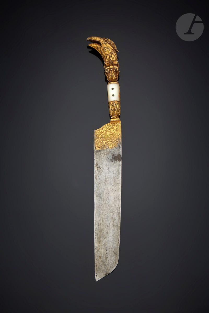 ITALY OR FRANCE SECOND HALF OF THE 16th
CENTURYServing
knife
partly in gilt bronze, the gilding continuing on the steel blade engraved with scrolls. The handle is successively decorated with a square of dots, acanthus leaves, two riveted mother-of-pearl plates and a Corinthian crown topped by the head of a bird of prey. Copper cutler's mark inlaid in the blade. This mark technique is found on a knife of the same period in the collections of the Victoria Albert Museum. 
Length : 30 cm - width of the blade : 3,4 cm

