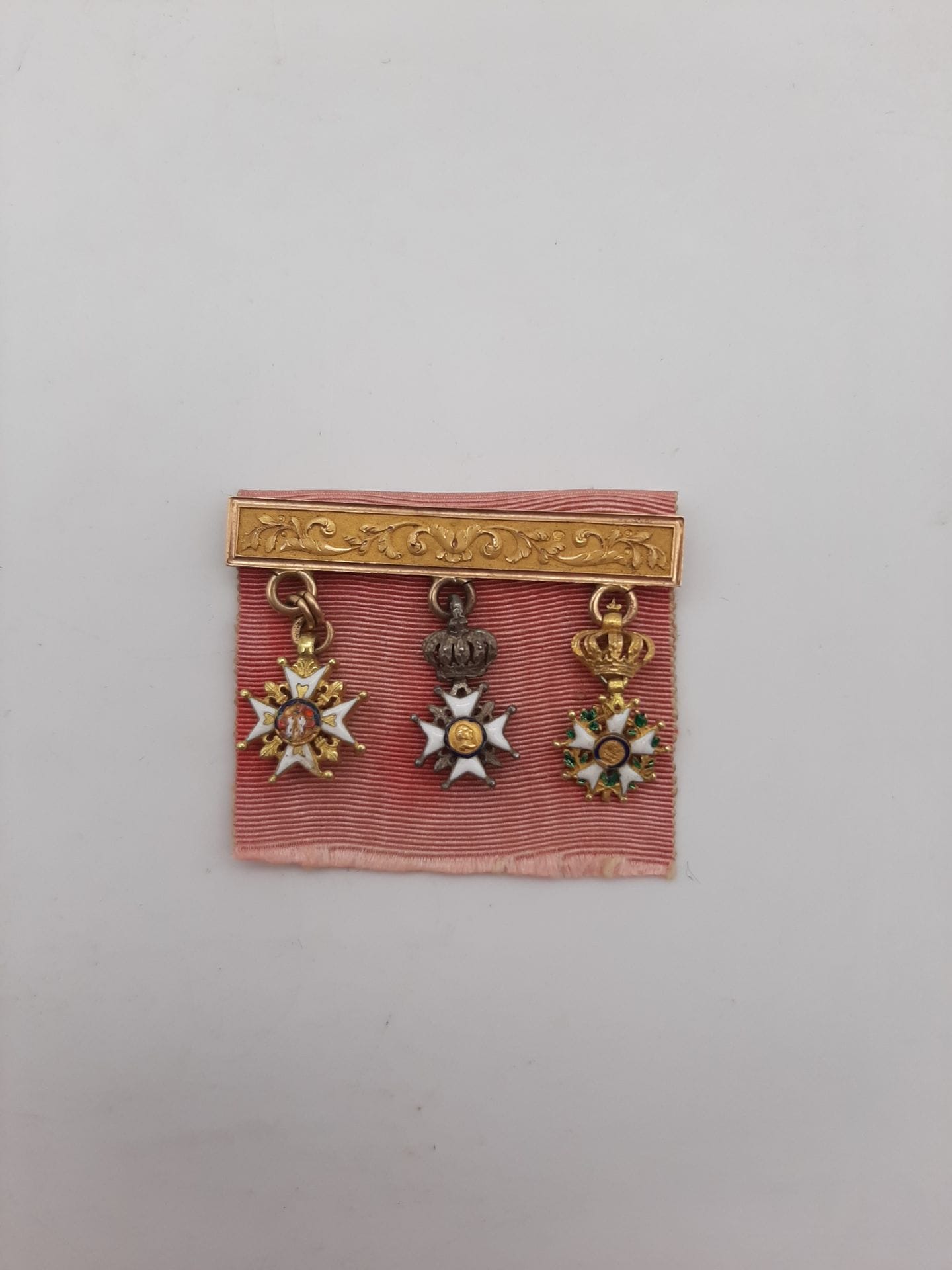 FRANCE 
Barrette en or ciselé, portant trois miniatures :
- croix de Saint Louis. En or et émail (petits éclats).
- croix du lys. En argent et émail. 
- étoile d’officier de la Légion d’honneur. En or et émail (petits éclats). 
Montée sur un ruban. 
35 x 24 mm - Poids brut : 5,4 g
T.T.B.