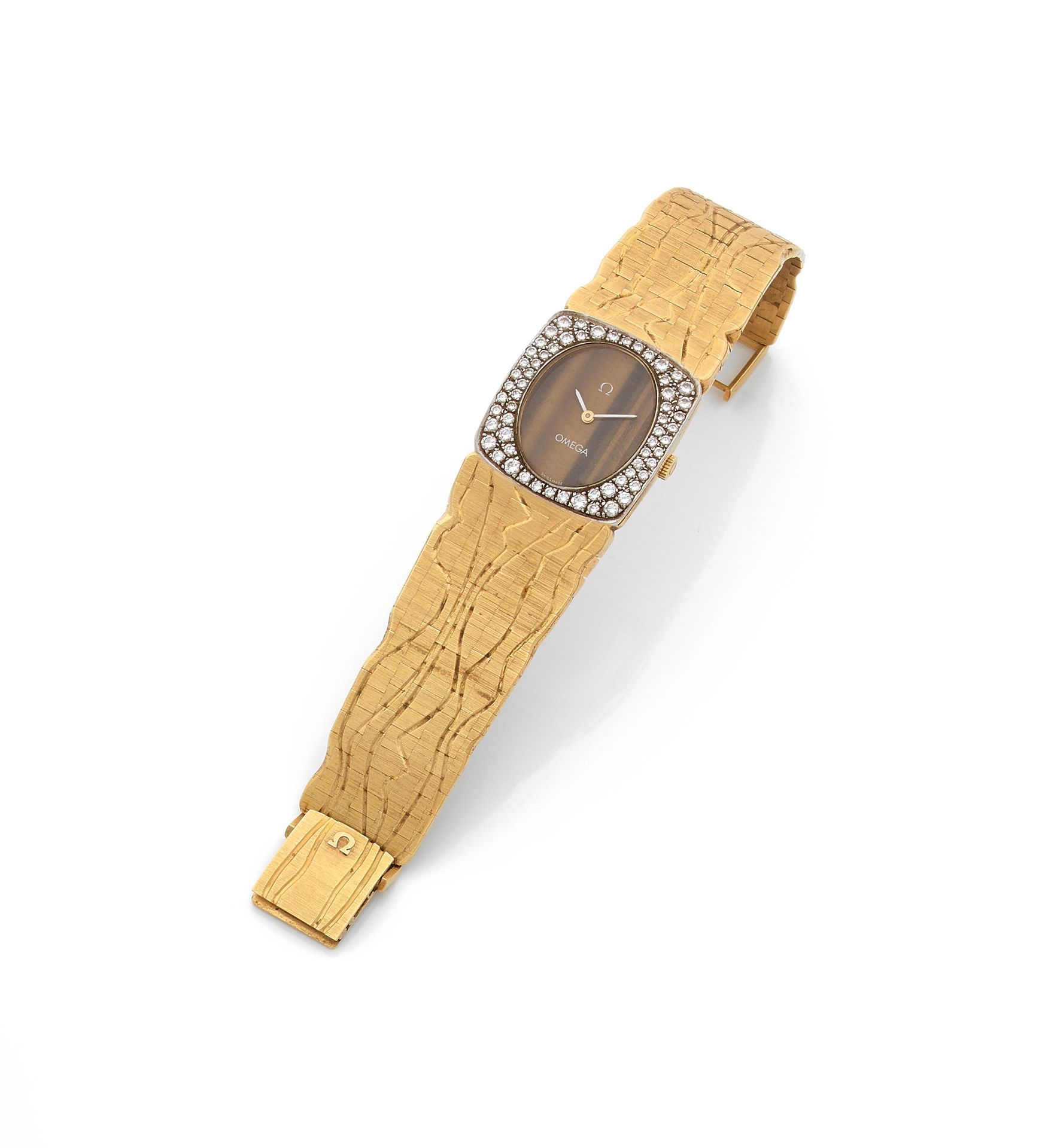 OMEGA. Vers 1970
N° 3858-0971
Montre bracelet de femme en or 18K (750), cadran en œil de tigre, lunette sertie de diamants taille brillant, mouvement à remontage mécanique calibre 620 N° 33424973, bracelet intégré en or 18K gravé de rainures, avec sa boucle signée.
Cadran, boîtier et mouvement signés.
Dimensions : 24,2 mm x 24,8 mm
Longueur : 16,5 cm 
Poids brut : 70,4 g