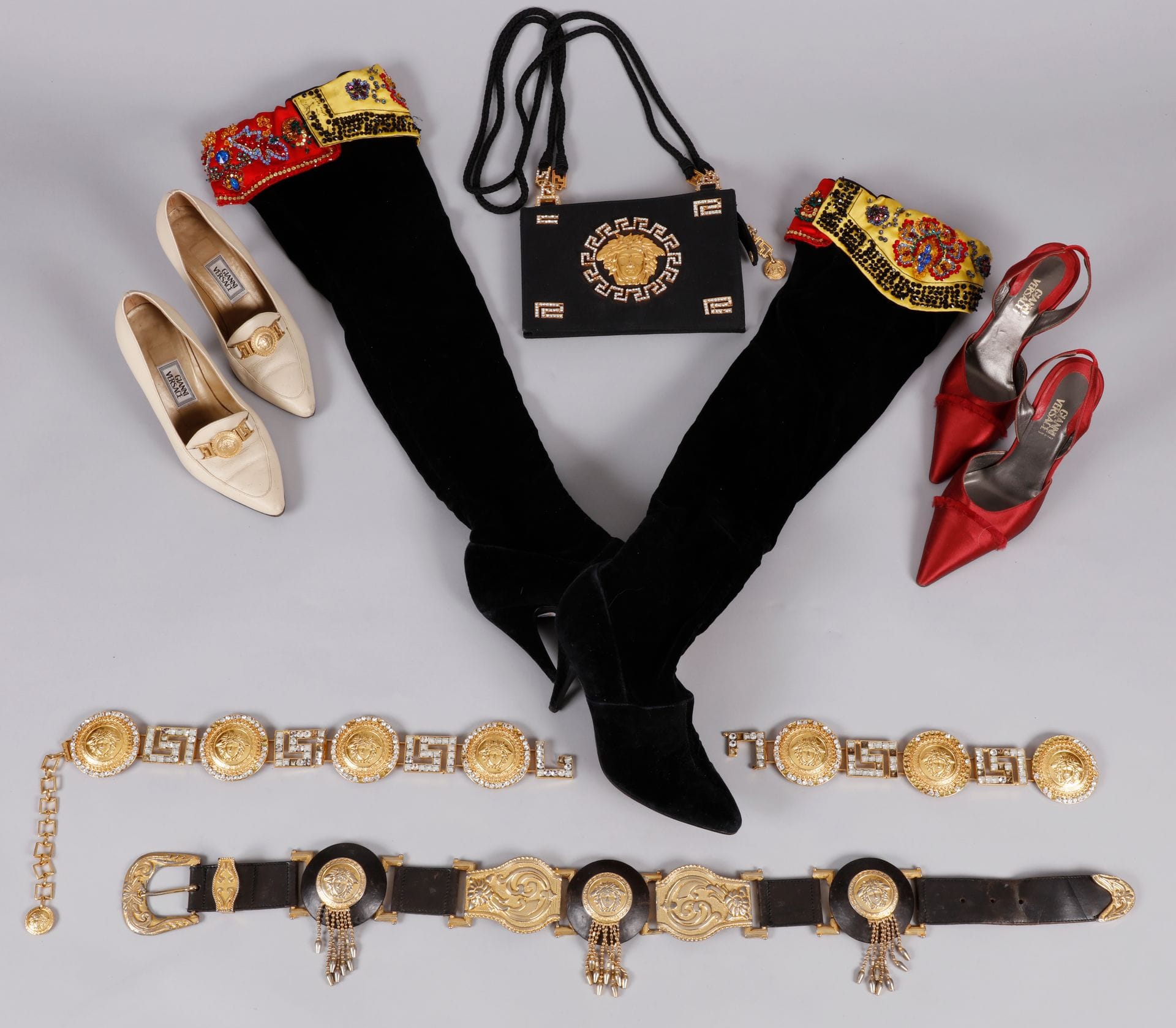 Gianni Versace. Lot de 6 pièces : 1 petit sac bandoulière en satin, métal doré et strass, 2 ceintures métal doré et strass et métal doré et cuir T.70 (accidents et manques), 1 paire de cuissardes en velours noir et strass et 2 paires d'escarpins T.37 env. (usures, en l'état)