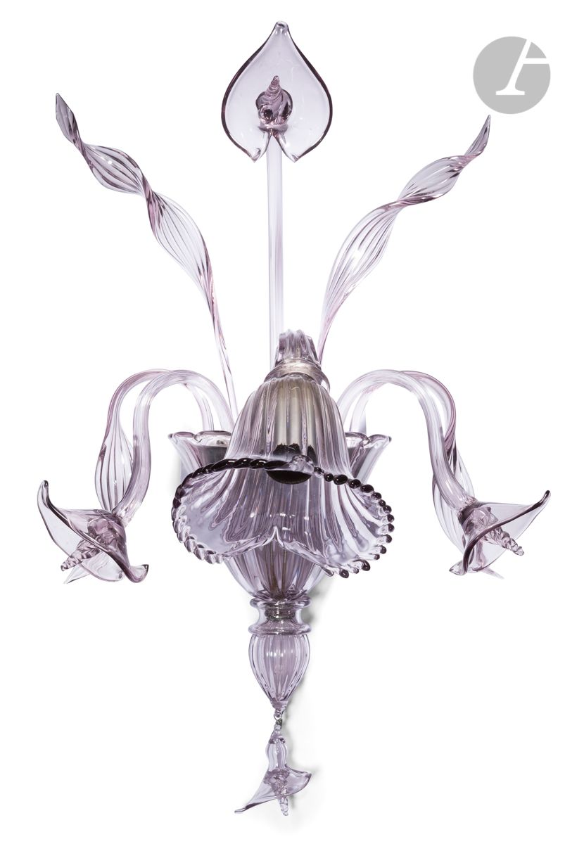 Applique en cristal fumé gris en forme de bouquet en verre moulé, soufflé, elle est composée de quatre feuilles et de 5 fleurs d’arum dont une en pampille. 
Les 12 éléments s’emboitent dans un socle en métal qui se fixe au mur.
Cette applique à une lumière rappelle l’esprit des lustres vénitiens dont l’apogée se situe du XVIe et XVIIIe siècle.
Murano, circa 1950.
H : 50 cm, L : 40 cm