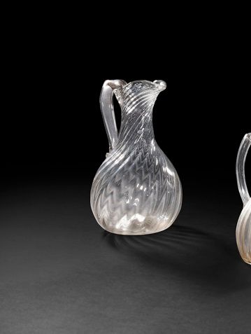 Grand pichet en verre soufflé à côtes tournantes à droite. 
Anse creuse en verre rapporté. Pontil non poli.
Normandie, XVIIIe siècle. 
H du bec verseur : 24,5 cm