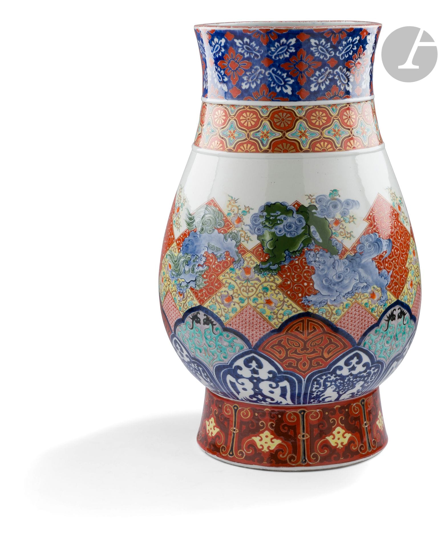 Vase en porcelaine à décor polychrome de shishi sur un fond de diverses frises à décor traditionnel, Japon, époque Meiji (1868-1912)
De forme inspirée de la forme chinoise archaïque zun, en porcelaine blanche décorée en bleu sous couverte et émaux polychromes sur couverte. Il est orné sur le col d’une frise de fleurs de style hanabishi rouges et blanches sur fond bleu et en dessous, d’une frise de motifs hiashi (rayons de soleil) dorés sur un ornement dit amime (oeil de filet de pêche), les intersections montrant des motifs géométriques floraux polychromes. La panse à décor de six shishi en bleu et vert sur un fond d’assemblage complexe de frises de formes diverses, d’abord une hokusaï monyô (décor créé par Hokusaï à partir du motif hishi: « diamant ») contenant alternativement karakusa (arabesques d’herbe) sur fond rouge, kake aoi (roses trémières suspendues) sur fond jaune et asa no ha (feuilles de chanvre) en rouge sur couverte. En dessous, deux bandeaux de kazan (montagne fleurie) sertis en bleu sous couverte à décor polychrome inspirés de décors archaïques, lapins lunaires, hoho, masque de taotie… Sur le pied une bande de dragons kui affrontés. Sous le pied une marque kotobuki - 壽 (longévité) et la marque 南里製 - « fait par Nanri ».
Hauteur : 63 cm
Grand fêle de cuisson sous le pied.

Nanri Kajū II (1817-1880) ou Higuchi Tahei est un potier du XIXe siècle ayant travaillé dans un four secondaire d’Arita, Zoshuntei Sanpo, four de Hizen, établi en 1841 pour fabriquer des articles spécialement destinés au commerce avec les Hollandais.