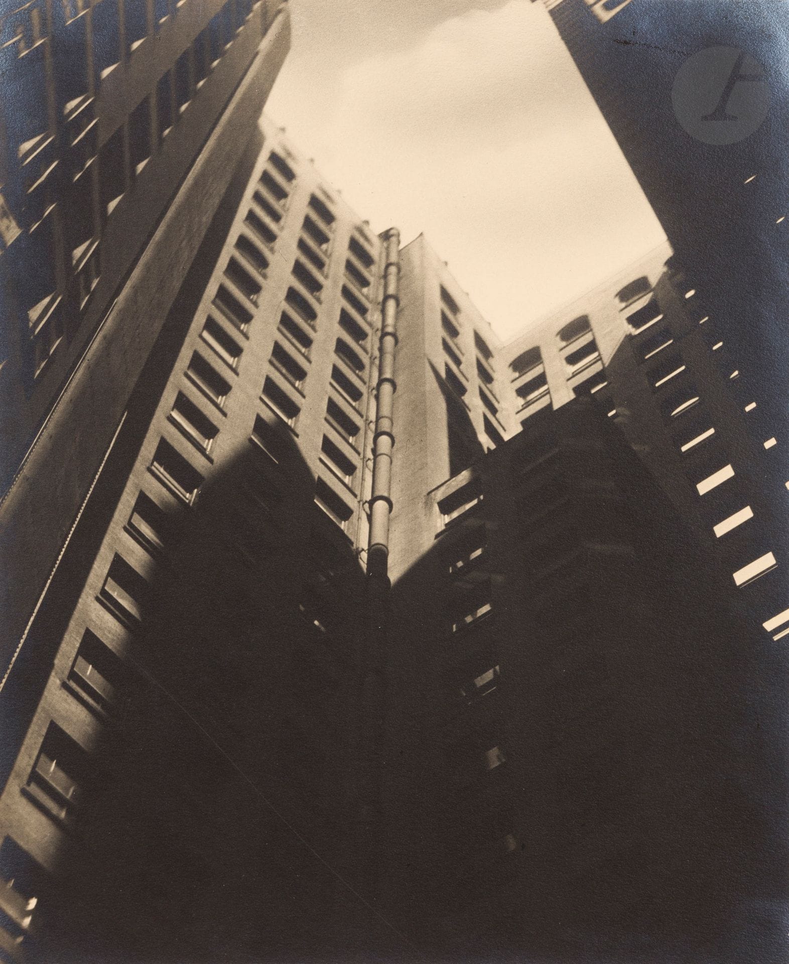 Sherril Schell (1877-1964) 
Number Ten. New York, c. 1930. 
Épreuve argentique d’époque, contrecollée sur carton, signée au crayon sur le montage en bas à droite. Titre au crayon au verso du montage. 
29x23cm

 D’abord photographe portraitiste en Angleterre, l’Américain Sherril Schell s’installe dans les années 1920 à New York dont la physionomie en pleine mutation devient l’objet principal de son travail. Déclinant le vocabulaire d’un modernisme photographique alors en cours d’élaboration (plongée, contre-plongée, cadrage visant l’abstraction, décontextualisation), ses épreuves sont exposées dès 1932 par Julien Levy aux côtés de celles de Berenice Abbott, Walker Evans ou Margaret Bourke-White (lors de l’exposition Photographs of New York by New York Photographers). Relativement méconnues aujourd’hui, ses oeuvres sont pourtant conservées dans de nombreux musées américains (Museum of the City of New York, MoMA, Art Institute of Chicago) et en son temps le photographe Adolf de Meyer collectionnait les vues modernistes de Sherril Schell.