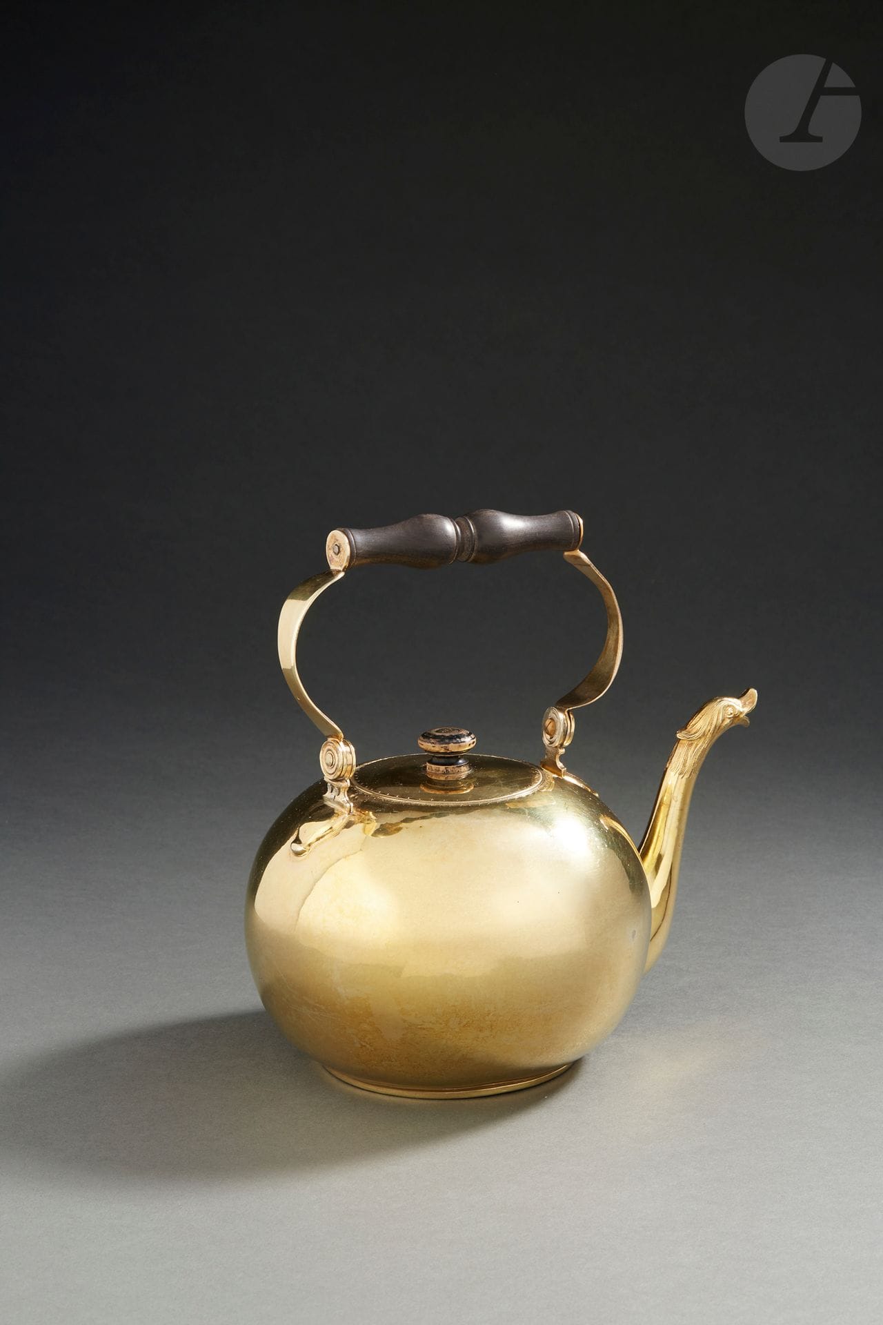 PARIS 1779 - 1780
Bouilloire en vermeil de forme boule à fond plat. L’anse, en forme d’étrier, reçoit une partie centrale en bois comme la prise du couvercle. La bordure du couvercle est ciselée d’une frise de demi-cercles et de points. Le bec verseur se termine par une tête d’oiseau huppée. 
Maître orfèvre : Jean-Louis OUTREBON, reçu en 1772
Poids brut : 599 g - hauteur : 20,5 cm
Poinçon : 1779 - 1780 lettre Q dans le couvercle, 1780 - 1781 lettre R pour le corps

Littérature : 
Un modèle similaire gravé est reproduit dans le livre de FAITH DENNIS Three Centuries of french domestic silver sous le numéro 269, page 182, datant de 1785 - 1786