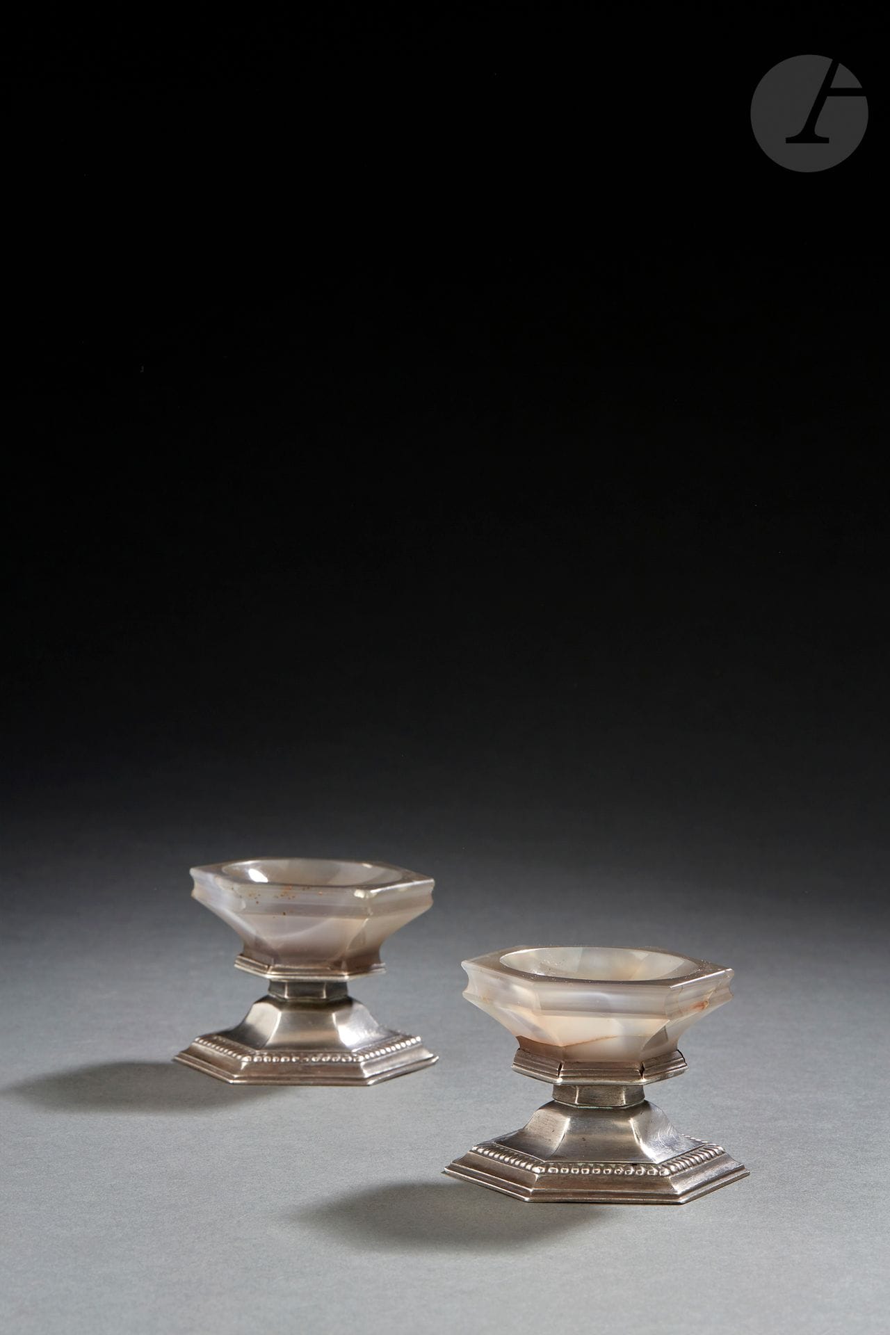 VERDUN CIRCA 1695 - 1700 or REIMS ?
Pair of silver saltcellars, the saltbushes in gray agate. The pedestal of hexagonal form is bordered of nets, then of godrons, form in recall on the hard stone.
Master goldsmith : attributed to SAINTELETTE or SAINCTLETTE
Marked by Jacques HELFT in his publication Poinçons des provinces françaises, n° 545 p. 198
Gross weight : 249 g - height : 5 cm
Condition : small lacks in the setting