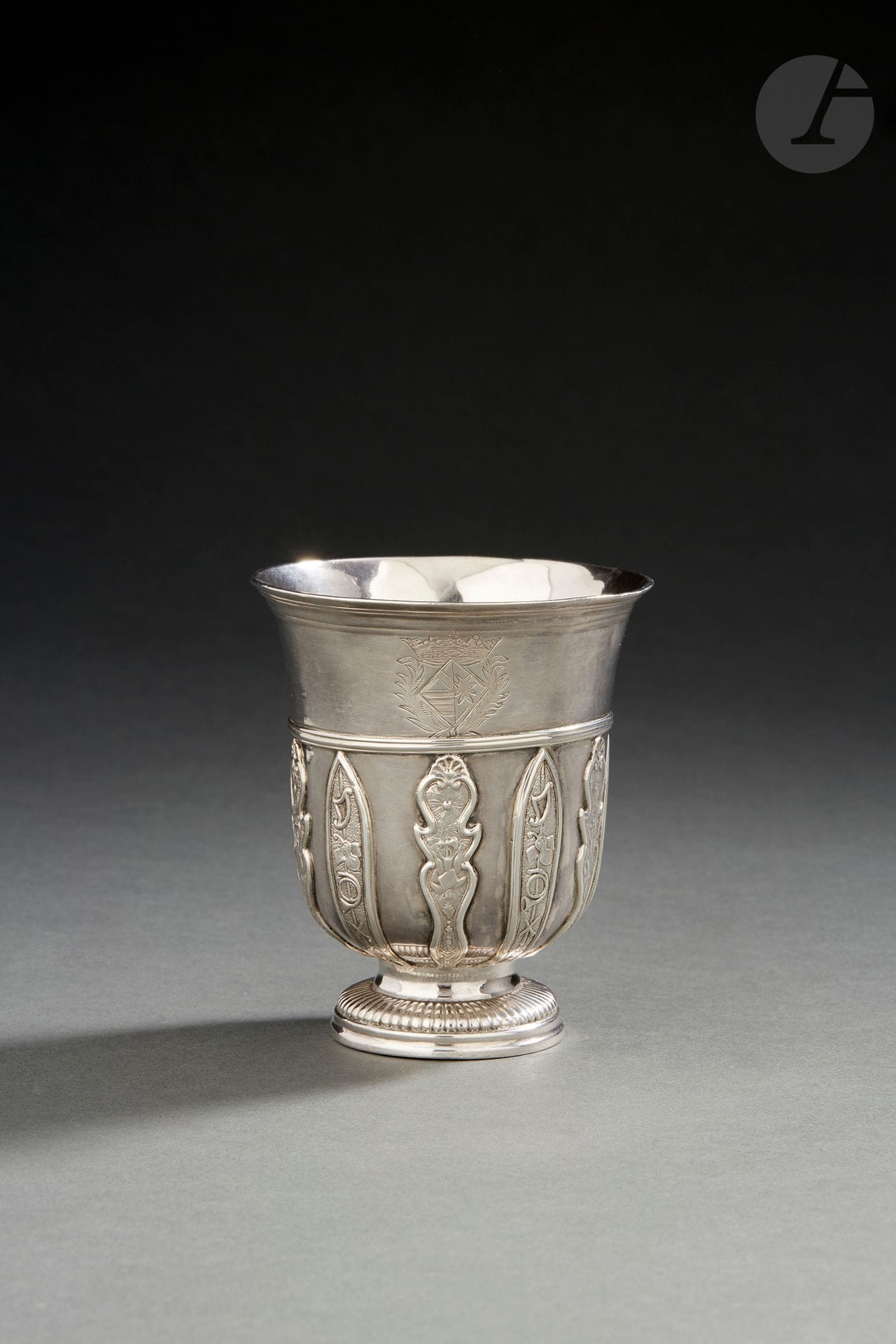 JURIDICTION D’ORLÉANS
Timbale tulipe en argent le piédouche mouluré de godrons, gravée d’une armoirie de jeune-fille sommée d’une couronne de marquis. Elle est décorée d’appliques en alternance, pour les lancéolées à décor d’instruments de musique, pour les lambrequins d’attributs guerriers sous un soleil rayonnant. 
Maître orfèvre : attribué à Laurent TREMBLAY qui travaillait à VENDOME
Poids : 181 g - hauteur : 9,2 cm