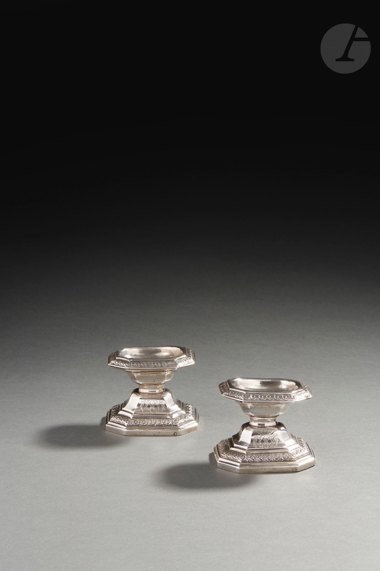 RENNES 1725 - 1726
Paire de salières en argent. Rare modèle français rappelant celui des salières de Liège dites « diabolo ». Elles reposent sur une base hexagonale à pans coupés en rappel sur la bordure supérieure, repoussée d’oves et d’entrelacs sur un fond amati. La partie supérieure sur les doucines est gravée des armoiries de jeune fille de René-Caroline-Victoire de Froulay (1714 - 1803), mariée en 1737 au marquis de Créquy (1686 - 1741). Elle tint salon à Paris durant tout le XVIIIe siècles.
Maître orfèvre : Jacques-Eloy PIGEON, reçu en 1725
Poinçonnée deux fois du maître orfèvre dans le fond et la base, décharge entre 1722 et 1726.
État : deux petits trous aux deux angles supérieurs d’une salière.
Poids : 219 g - hauteur : 6,5 cm - longueur : 8 cm - largeur : 6,5 cm