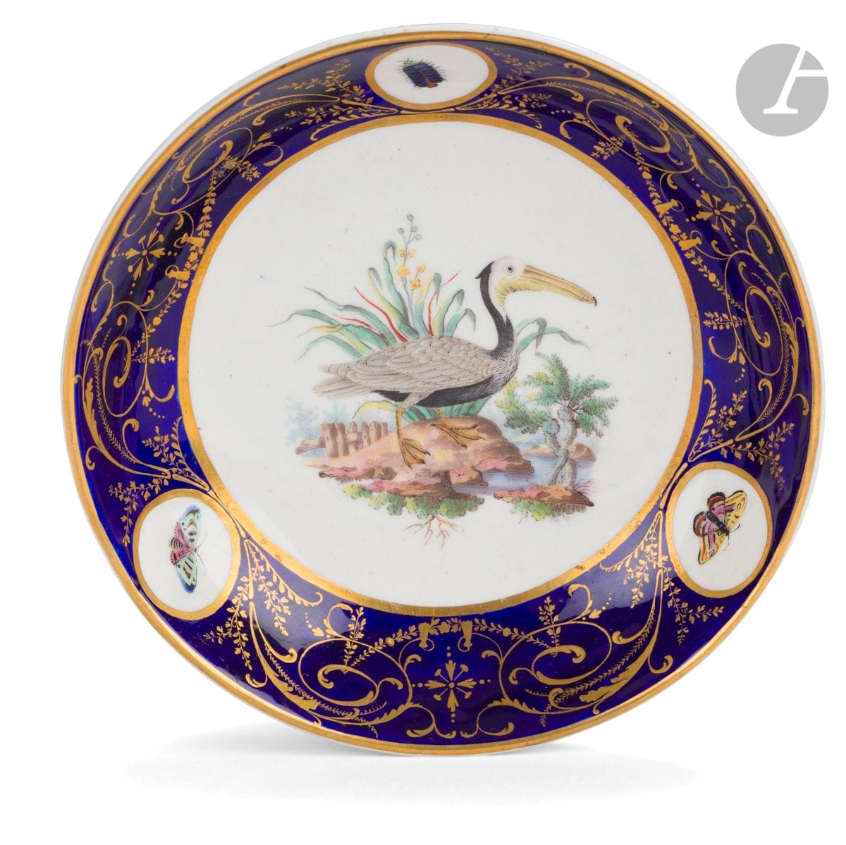 Tournai
Soucoupe en porcelaine tendre du service du duc d’Orléans à à décor polychrome d’après l’Histoire naturelle des Oiseaux du comte de Buffon au centre d’un oiseau nommé en noir au revers : pélican brun, d’Amérique, le bord décoré de papillons et insecte dans trois médaillons sur fond bleu orné de rinceaux feuillagés en or.
XVIIIe siècle, vers 1787.
D. : 13,5 cm