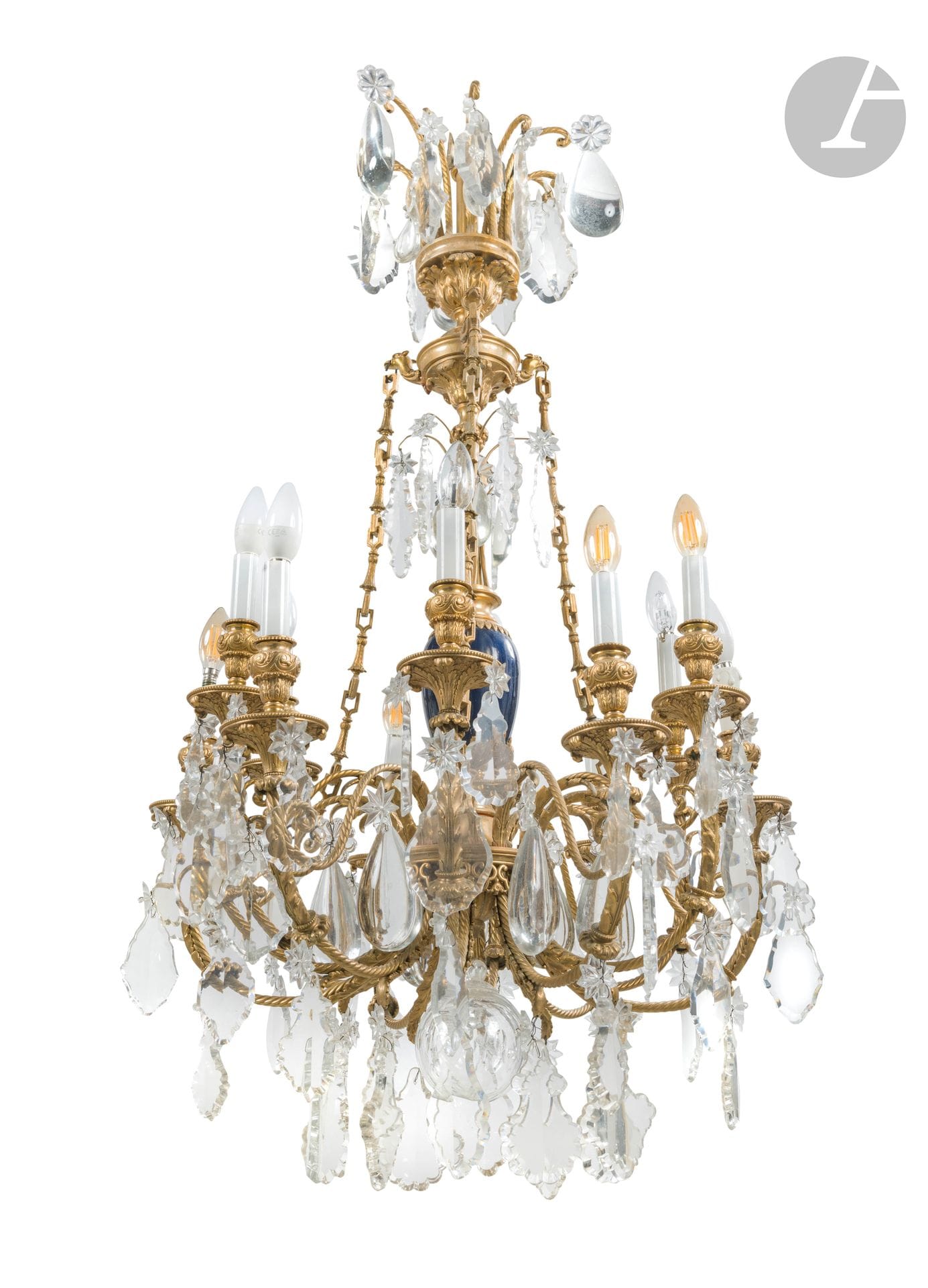 Lustre en bronze doré, verre taillé et porcelaine bleu, à douze bras de lumière torsadés, feuilles d’acanthe et motifs trilobés, à décor de pendeloques et étoiles, monté à l’électricité ; (accidents et manques).
Style Louis XVI.
H. : 120 cm, L. : 66 cm