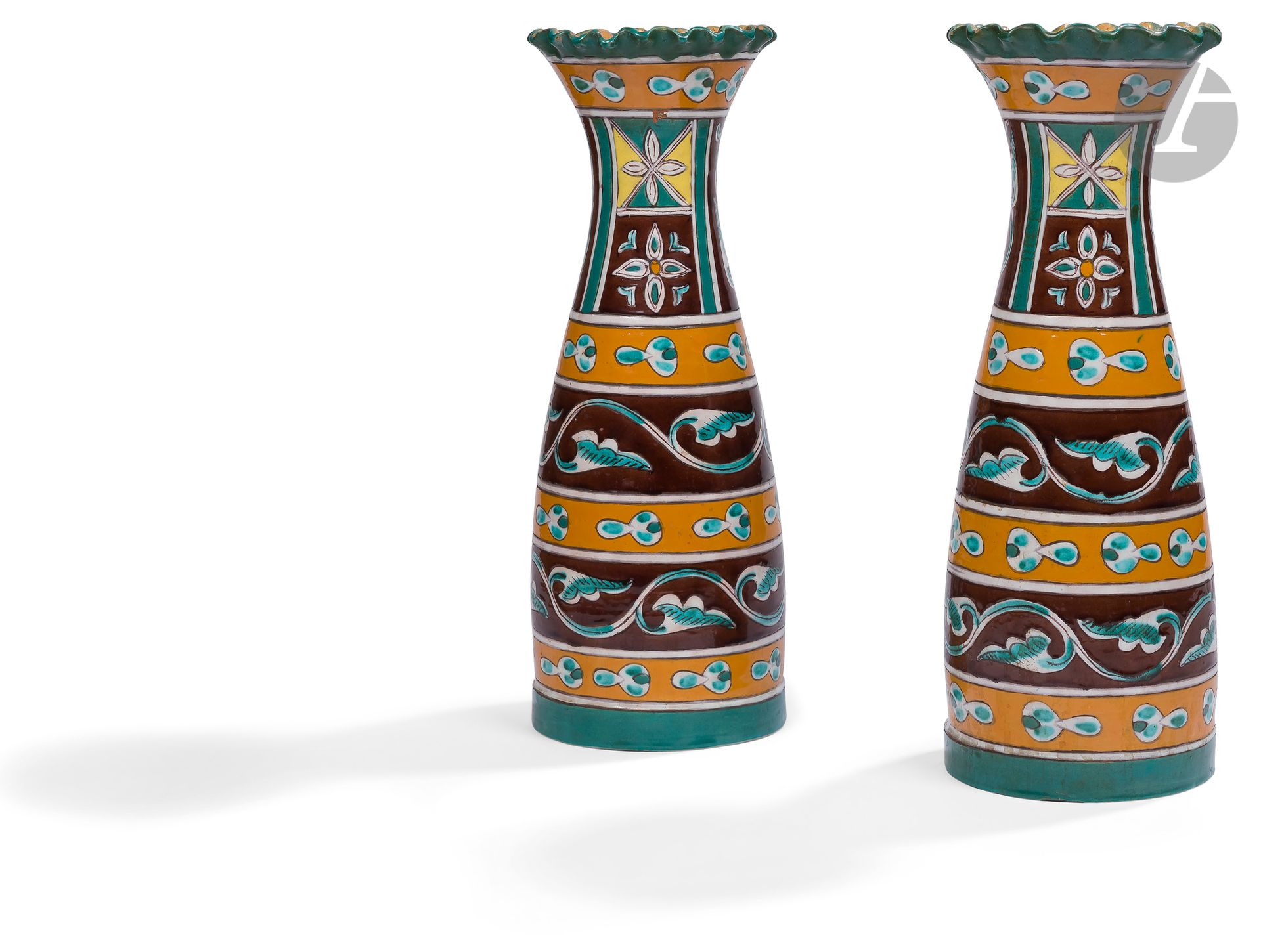 Paire de vases en collerette, Tunisie, Nabeul, Maison Tissier, vers 1905
Vases de grande taille en faïence à panse cylindrique resserrée vers le col ouvert en collerette ondulée. Décor peint en plusieurs registres horizontaux sur la panse et verticaux sur le col, des frises de rinceaux sur fond brun alternant avec des frises de cintemani stylisés sur fond jaune sur la panse et des motifs de quadrilobes sur le col. Sous la base, estampille en arabe de la maison Tissier “Tissier Nabeul”.
Hauteur : 39 cm
Éclats.

A Pair of Pottery Vases, Tunisia, Nabeul, Tissier Factory, c. 1905 

La poterie artistique de Nabeul : Maison Tissier (lots 189 à 191) - Collection Samuel Hedri (lots 174 à 212).