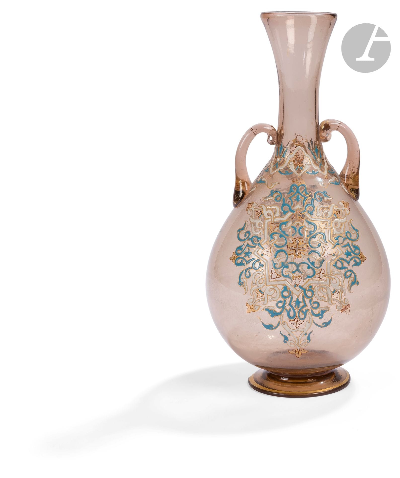 Vase en verre émaillé, dans le goût de Brocard, Europe, XIXe siècle
Vase à panse piriforme sur pied annulaire, le col évasé et flanqué de deux anses. En verre fumé à décor émaillé d’une rosace étoilée à cœur cruciforme et garnie d’entrelacs de palmettes, une frise végétale courant à la base du col. 
Hauteur : 25 cm
Accident au talon.

A Brocard Style Enameled Glass Vase, Europe, 19th century