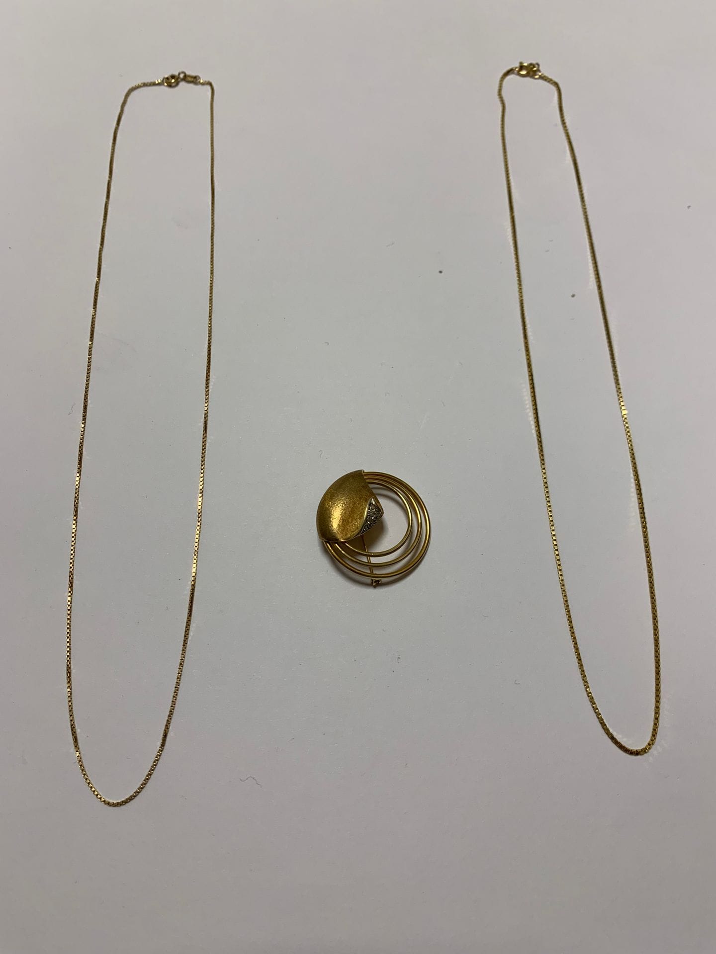 Lot de bijoux en or (14K). Poids brut : 15,6 g - chaines fines maillons carrés (50 et 53 cm) - broche cercles concentriques et pierres blanches
