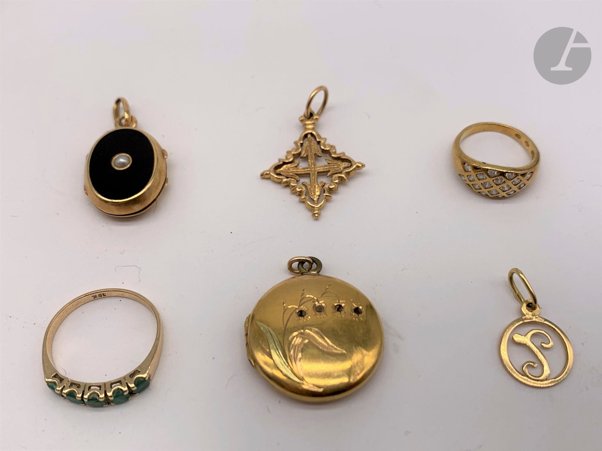 Lot de bijoux en or (18K). Poids Brut: 13,1 g - un pendentif muguet cadre ouvrant (sans verre). - un pendentif ovale noir cadre ouvrant (verre et mèche de cheveux) - un pendentif croix - un pendentif lettre - une bague avec pierres vertes (T.52). On joint une bague en or (14K) et pierres blanches (T.41). Poids: 2,1 g