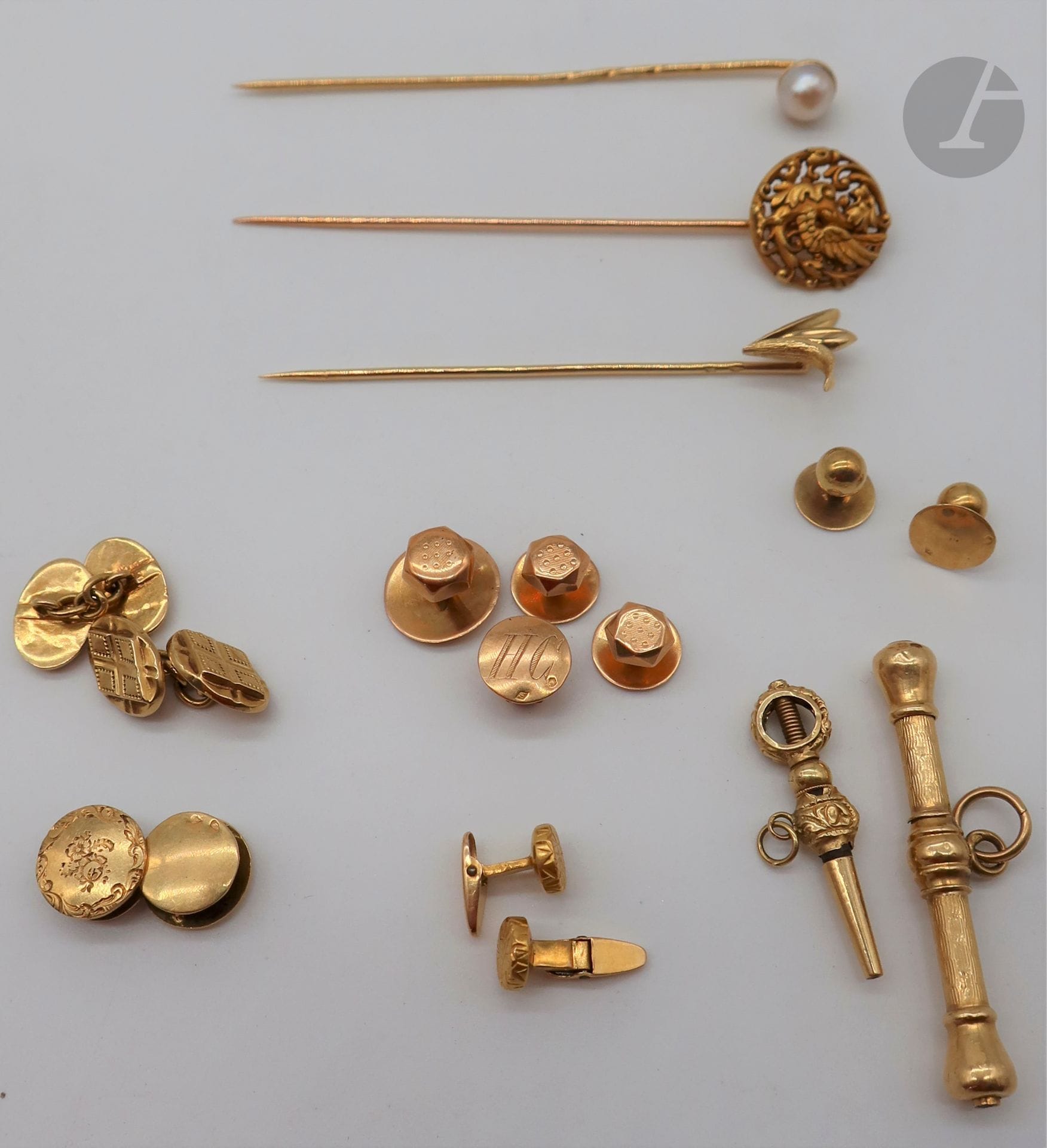 Lot de bijoux en or (majoritairement 18K). Poids brut: 25,2 g - 3 épingles (dragon, blé, perle). - 2 élément de chaine de montre (barre et clef). Poids brut: 6,3 g - 2 paires de boutons de manchette (dont 1 en or 22K et 14K). - 2 paires de bouton de col - 4 boutons de col et plastron (lettrés HC)