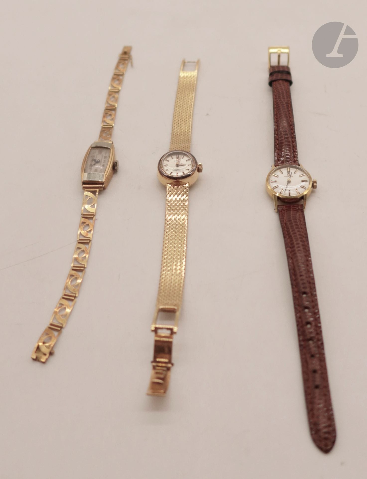 3 montres de femme en or (18K). Poids brut : 62,6 g - OMEGA : boitier et bracelet en or. Poids brut : 39,1 g - OMEGA : boitier en or, bracelet cuir et fermoir en métal. Poids brut: 11,4 g - boitier 2 ors et bracelet ajouré en or. Poids brut: 12,1 g