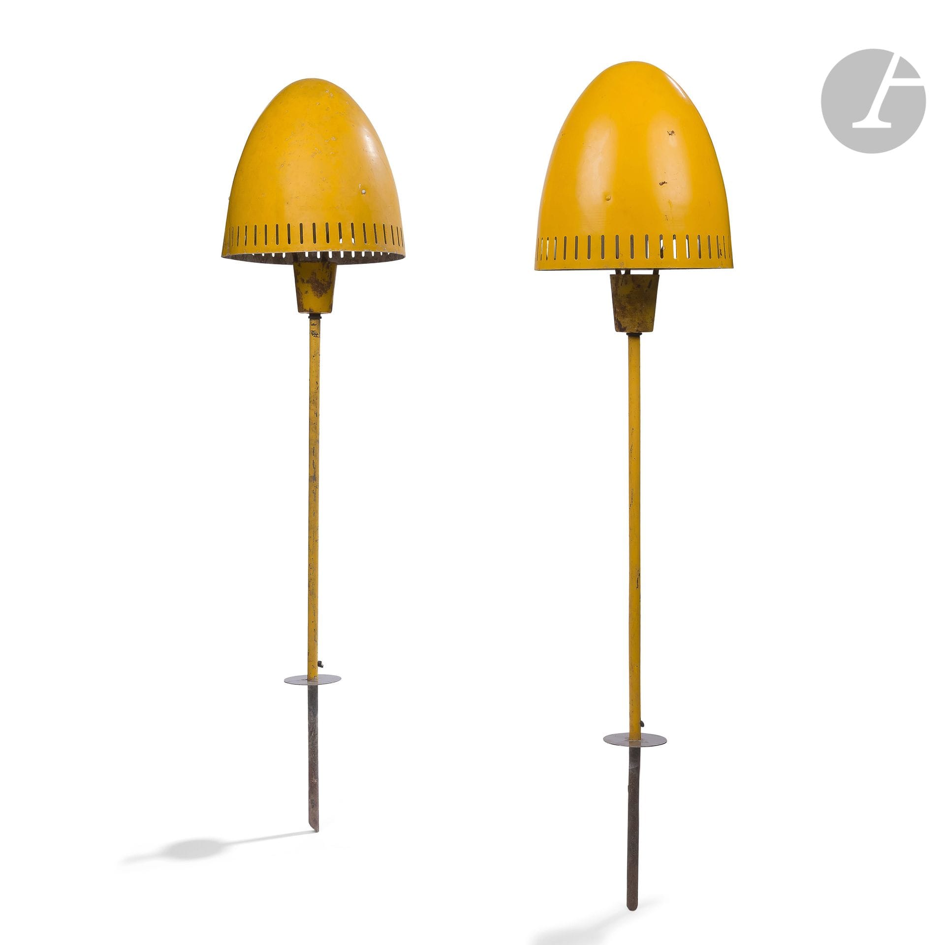 TRAVAIL DES ANNÉES 1950-60
Paire de lampes de jardin à planter en métal laqué jaune. Les fûts tubulaires complets de leur garde, les cache-ampoules en ogives et aux perforations verticales. Sauts de laque, importantes oxydations. H. 122 cm