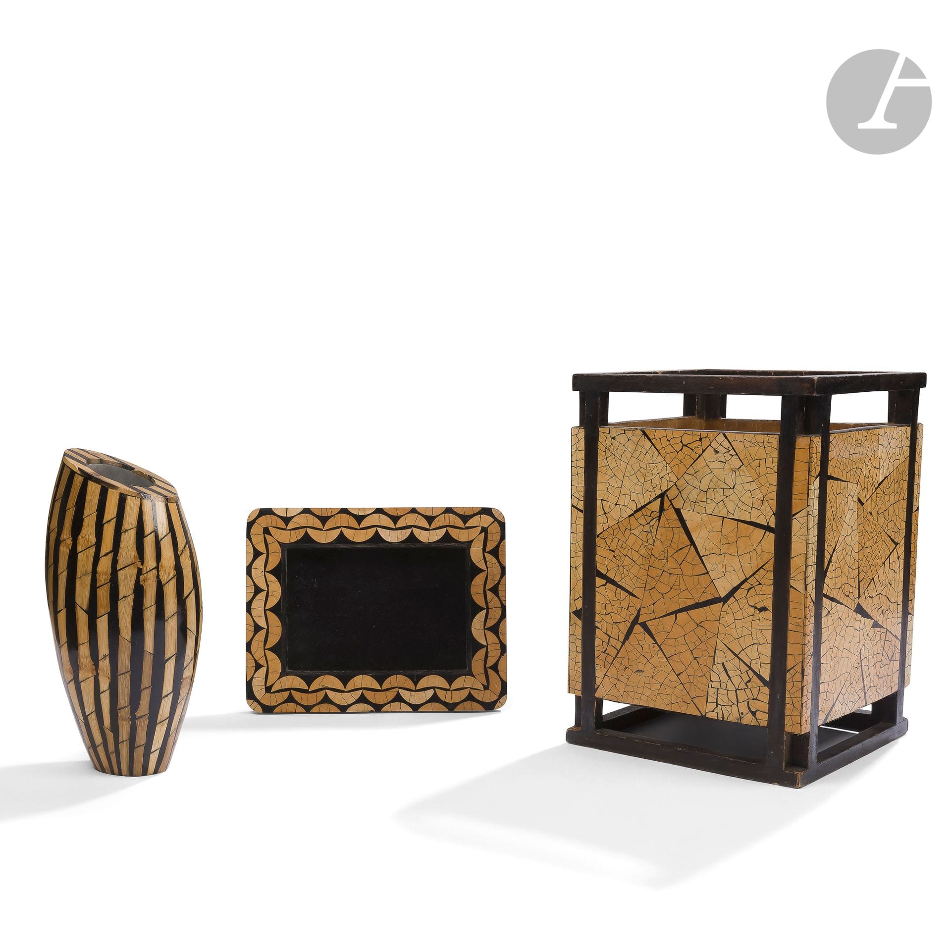 RIA & YIOURI AUGOUSTI (FOUNDED IN 1989) - 3 WORKSSet
including a wastepaper basket, a vase and a picture frame.
- Basket; the structure in stained wood veneer and the body in coconut marquetry on resin stained in the mass, imitating the eggshell; the reverse side upholstered in imitation leather. Lacks and jumps of veneer, wear marks to the imitation leather. Stamped R & Y AUGOUSTI London under the base. H. 30 cm - L. 20,7 cm - W. 20,5 cm -
Truncated ovoid vase in bamboo marquetry on resin tinted in the mass, the receptacle in metal; the reverse lined with imitation leather
.
Stamped R & Y AUGOUSTI Paris under the base. H. 24,5 cm - L. 12,5 cm - W. 11 cm-
Rectangular frame with rounded corners and geometrical patterns in marquetry of coconut on resin dyed in the mass; the interior and the back lined with velvet
.
It bears the metal plate R & Y AUGOUSTI London on the back. H. 23,1 cm - W. 18 cm - D. 17,5 cm



