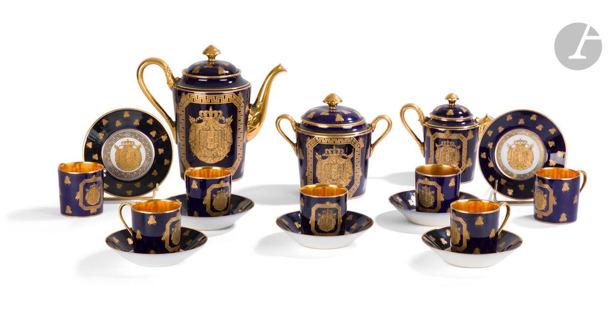 Paris
Partie de service en porcelaine à décor en or sur fond bleu des grandes armes impériales et semis d’abeilles comprenant une théière couverte, un pot à sucre couvert, un pot à lait couvert, sept tasses litron et sept soucoupes. 
Marque apocryphe de la manufacture de Sèvres. 
Fin du XIXe siècle. 
Deux tasses et une soucoupe accidentées.