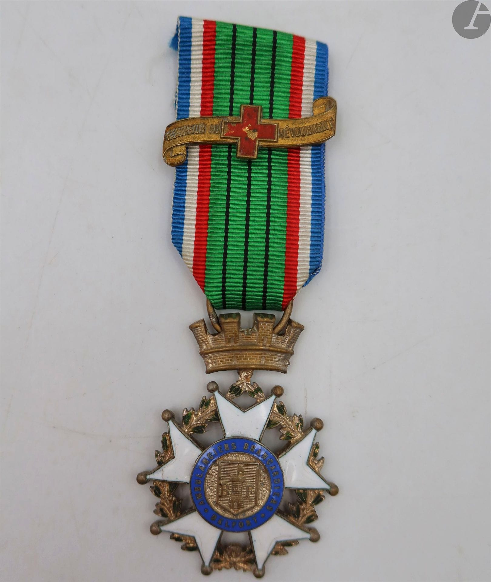 FRANCE
MÉDAILLE DES AMBULANCIERS BRANCARDIERS DE BELFORT. 
Métal argenté et émaillé (cheveux). Ruban postérieur à agrafe ancienne « HONNEUR AU DÉVOUEMENT » à la croix-rouge peinte.
55 x 41 mm
T.B.