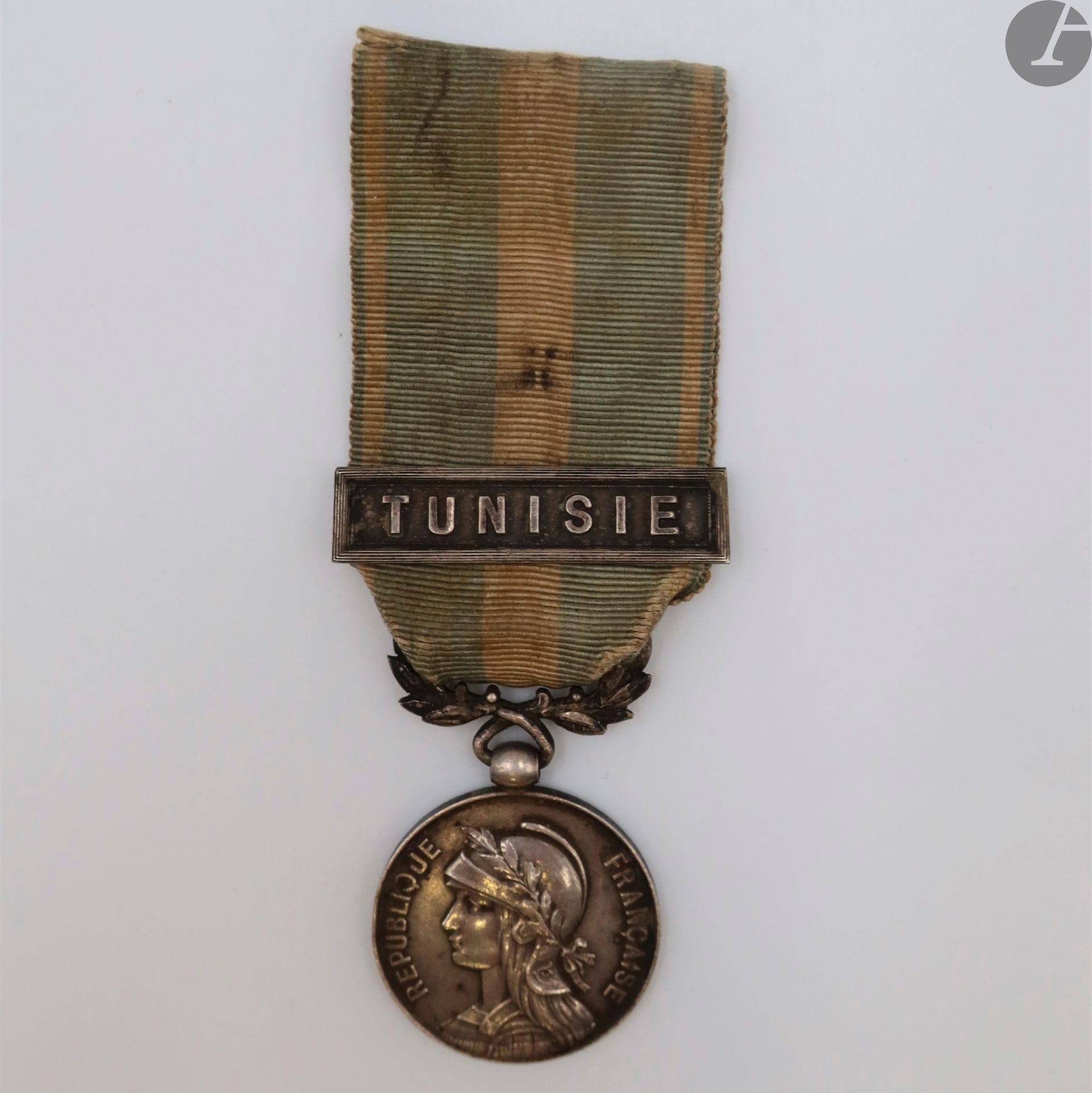 FRANCE
MÉDAILLE COLONIALE (1893)
Médaille coloniale du 1er type, modèle non signé « à l’épaule basse ».
En argent, non poinçonné. Bélière biface.
Ruban (sale) à agrafe « tunisie ».
Hauteur : 42 mm - Diamètre : 28 mm - Poids brut : 20,5 g
T.T.B. Intéressant défaut de frappe dans la bordure inférieure.