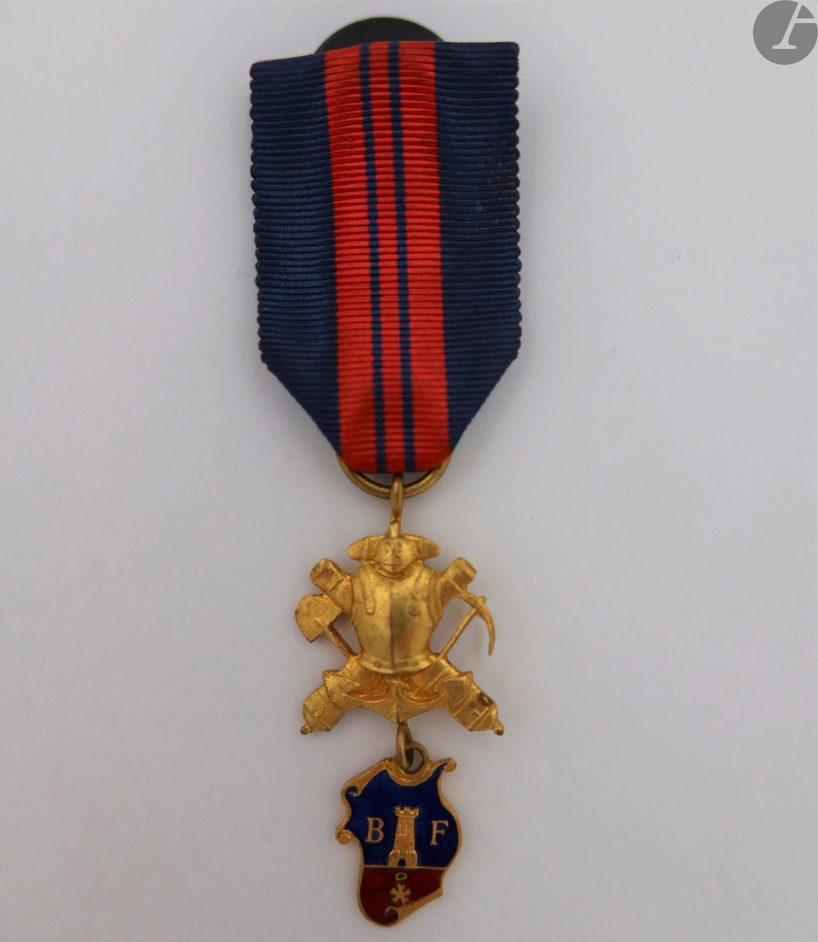 FRANCE
INSIGNE D’UNE ASSOCIATION DITE « DES ANCIENS SAPEURS DU SIÈGE DE BELFORT. »
En métal doré et émaillé.
42 x 21 mm
Ruban à attache de boutonnière. 
T.T.B. à SUP.