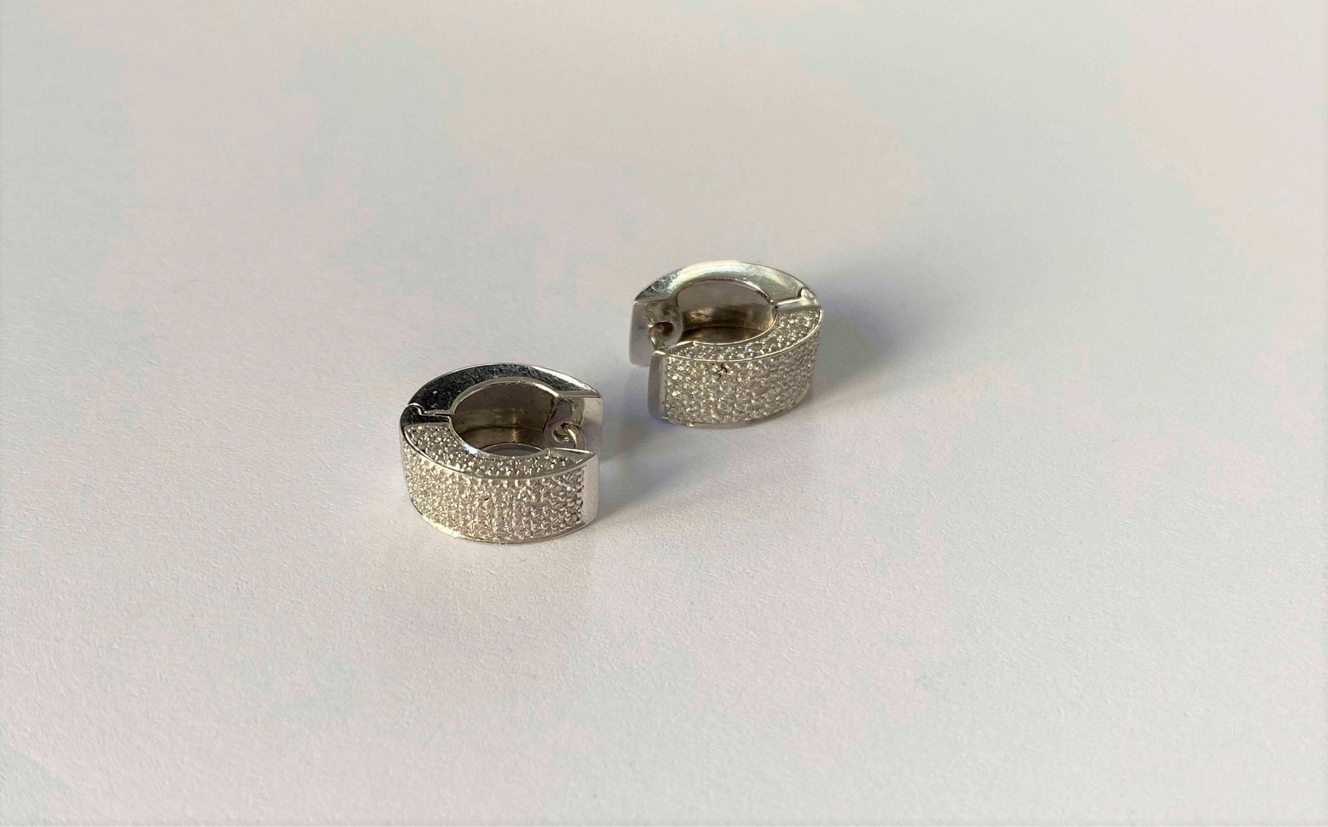 Paire de créoles en or gris 18K (750), à demi-pavées de diamants ronds de taille brillant. Hauteur : 1,2 cm environ. Poids brut : 7,1 g (manque)