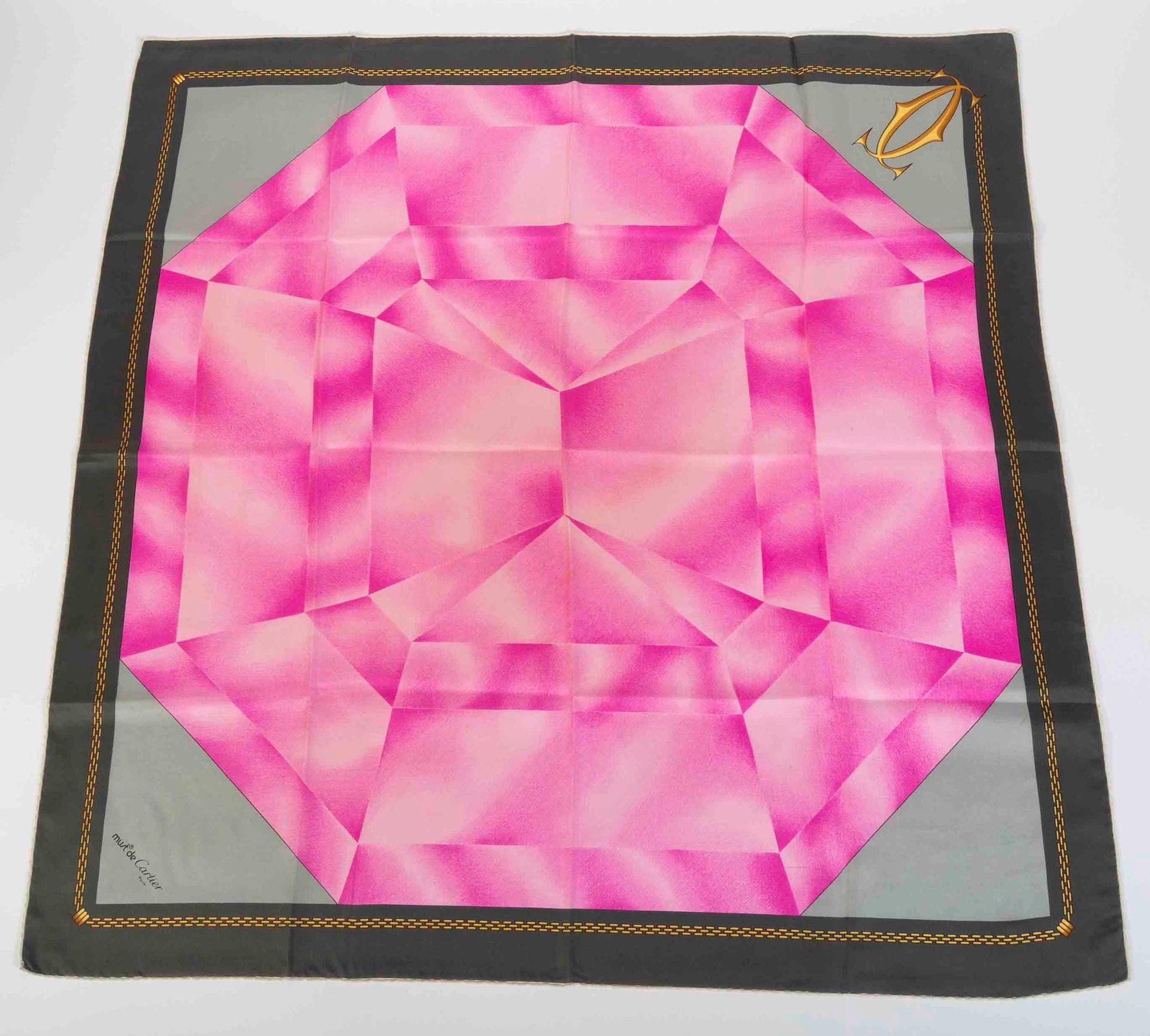 Must de CARTIER
Foulard en soie à décor de diamant rose, entourage gris, étui cartonné (quelques salissures)