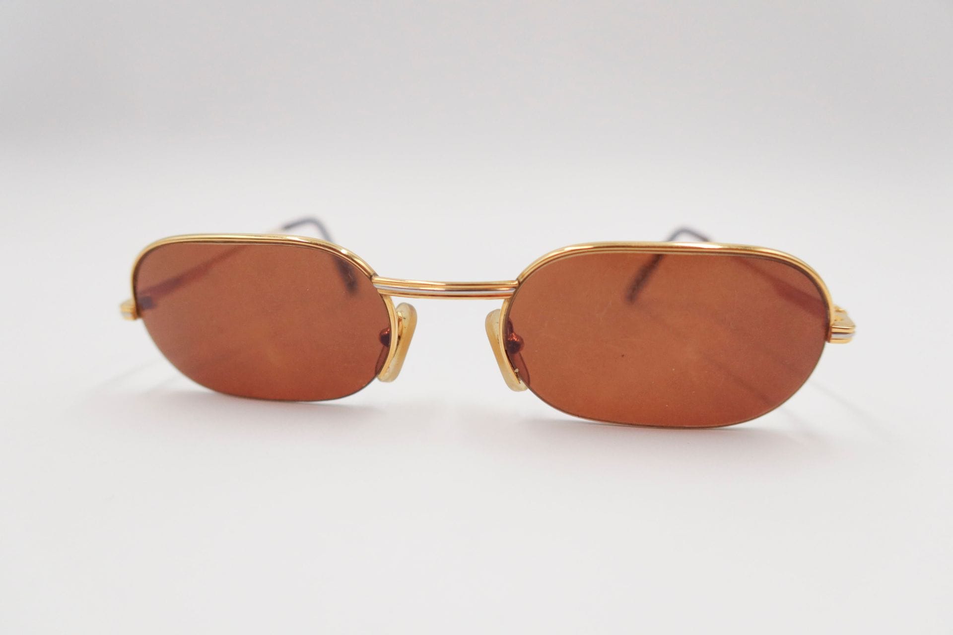 CARTIER
Paire de lunette de soleil pour homme en métal finition dorée et grise, forme ovale et verres marron. Signée. Longueur des verres : 5,3 cm. Poids brut : 18,7 g (usures, rayures)