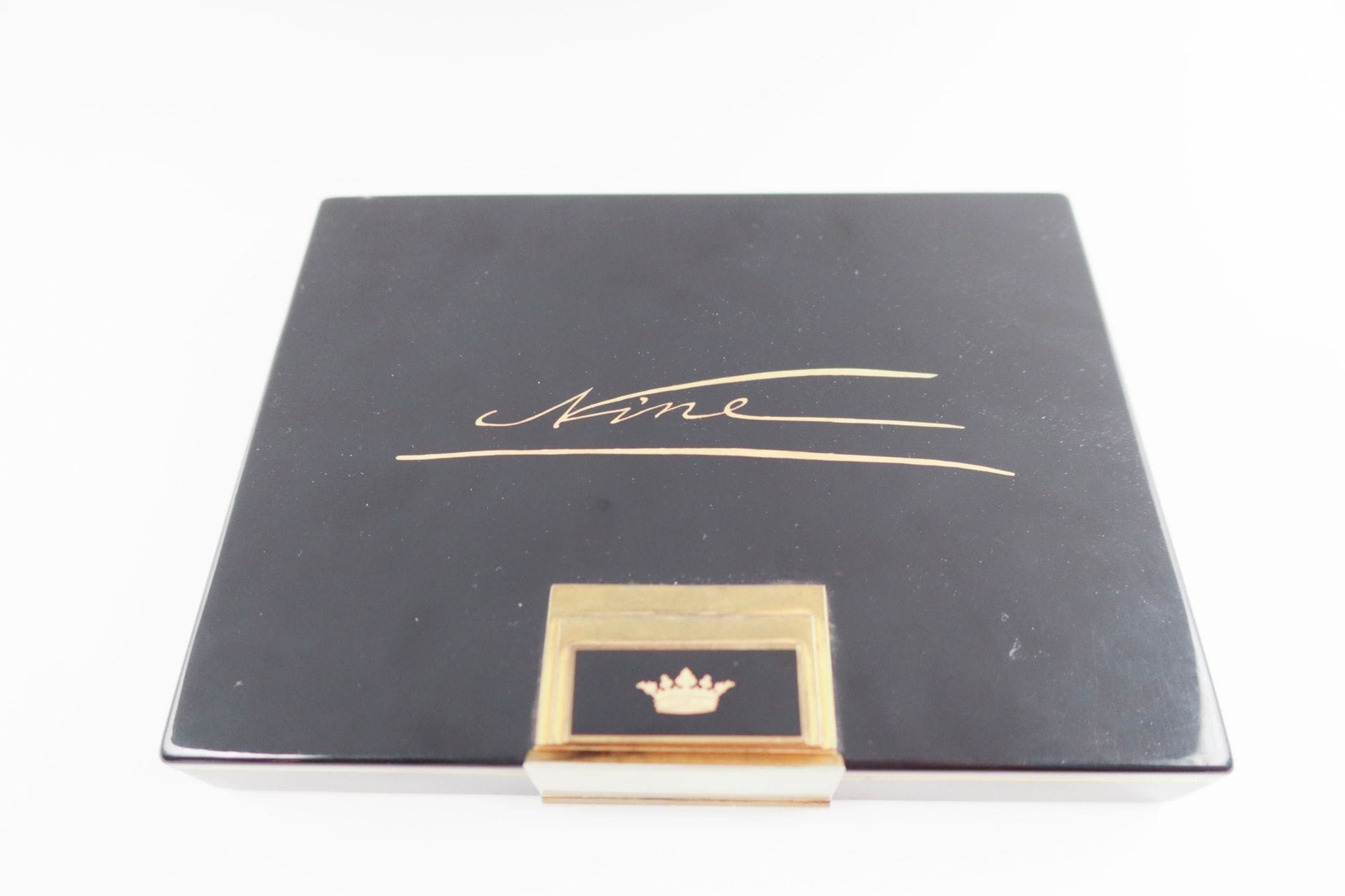 S.T. DUPONT
Nécessaire du soir en métal doré, émaillé noir le couvercle orné d'une gravure personnalisée "Nine" ainsi que d'un motif de couronne ; l'intérieur recèle un miroir biseauté (cassé), 2 poudriers, 1 peigne en écaille, 1 étui de rouge à lèvres, 1 compartiment pour briquet, un autre pour cigarettes. Signé. Conservé dans sa boîte d'origine. Dimensions : 16 x 11,5 x 2 cm environ (choc, traces d'usures, manque le briquet)