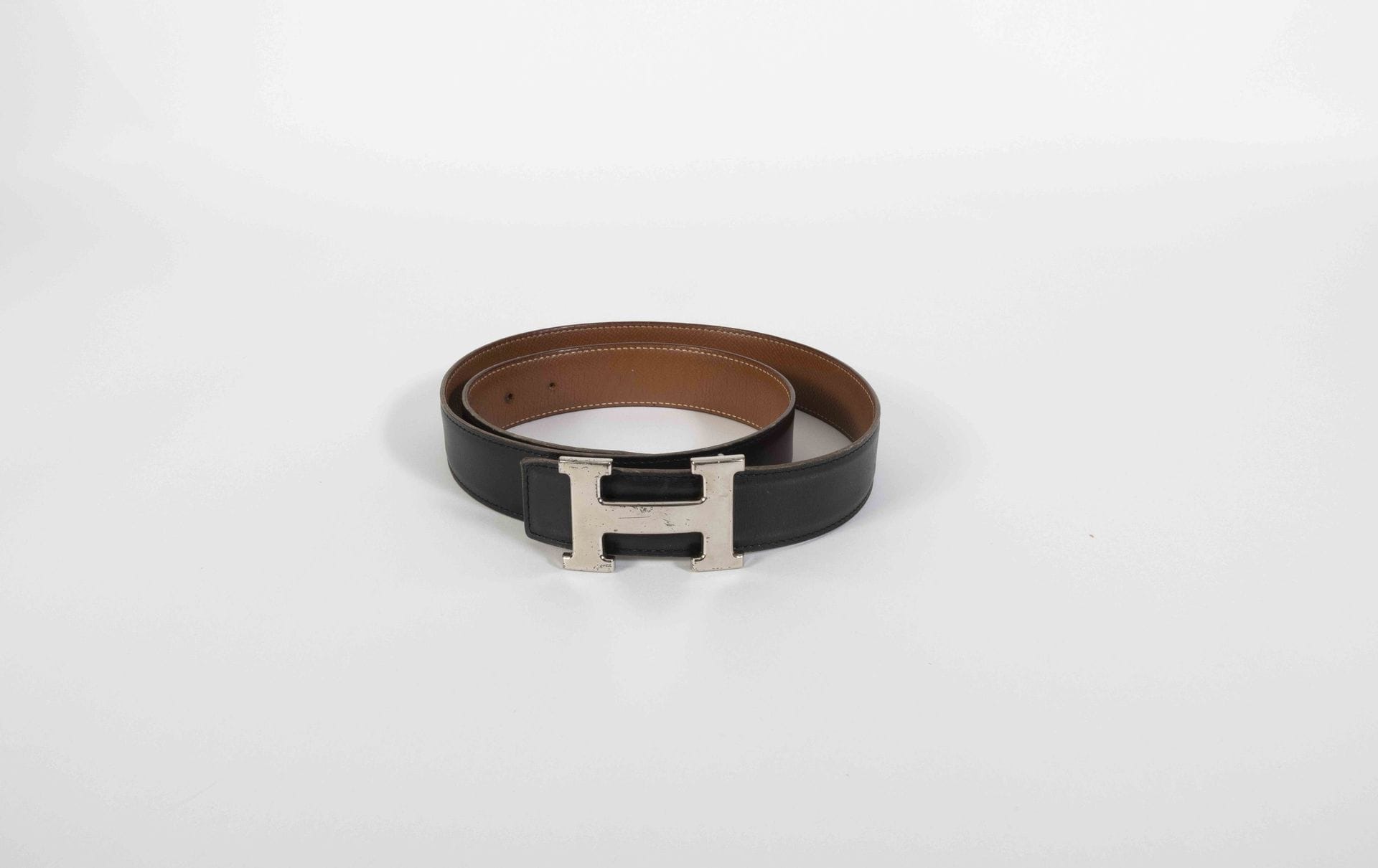 HERMES Paris Made in France. Circa 1995
Ceinture en cuir grainé gold et cuir lisse noir, boucle de ceinture H en métal argenté, T.85
(usures et marques)