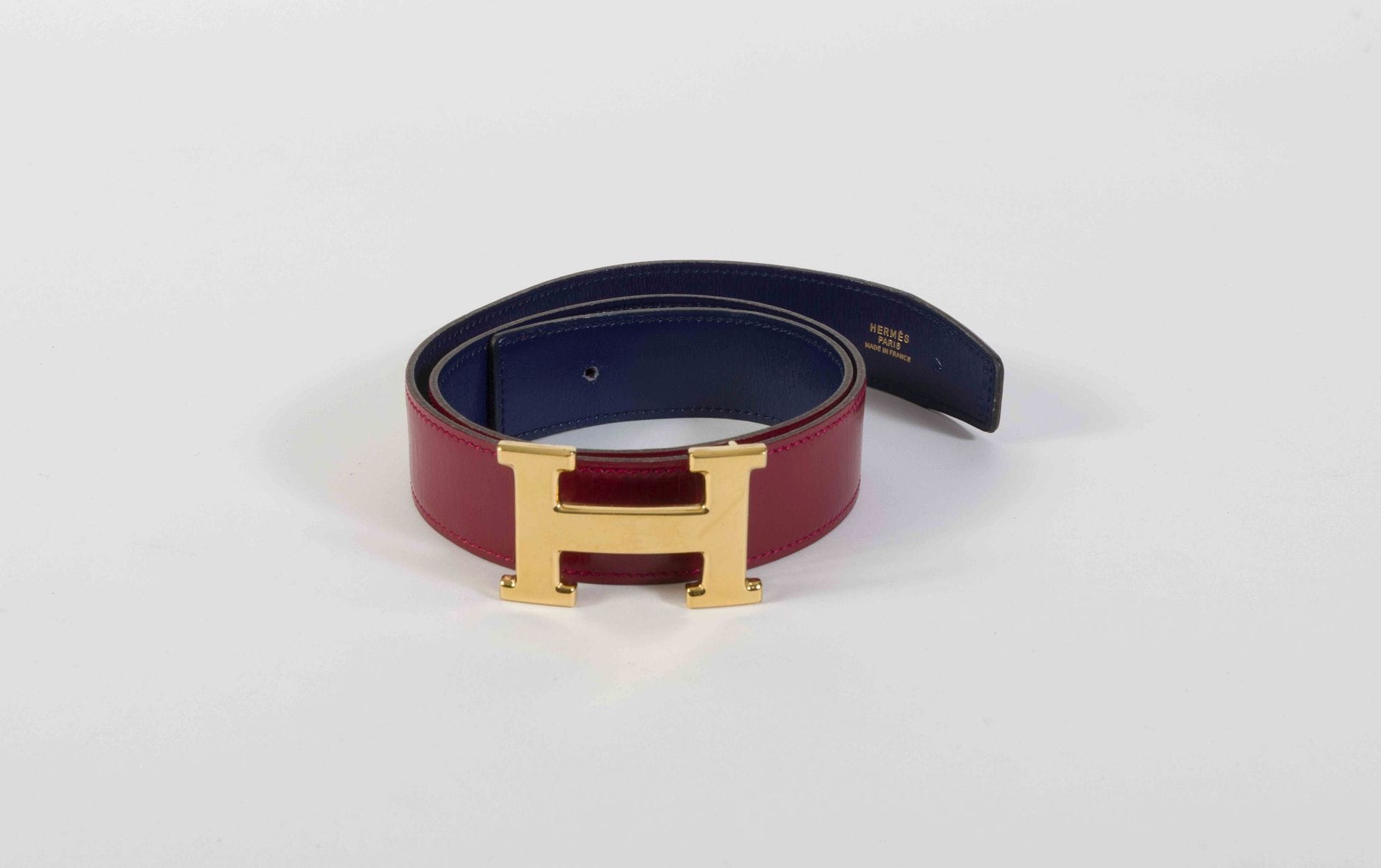 HERMES Paris Made in France. Circa 1990
Ceinture en cuir marine et rouge, boucle H en métal doré (rayures à la boucle), T.70, boîte