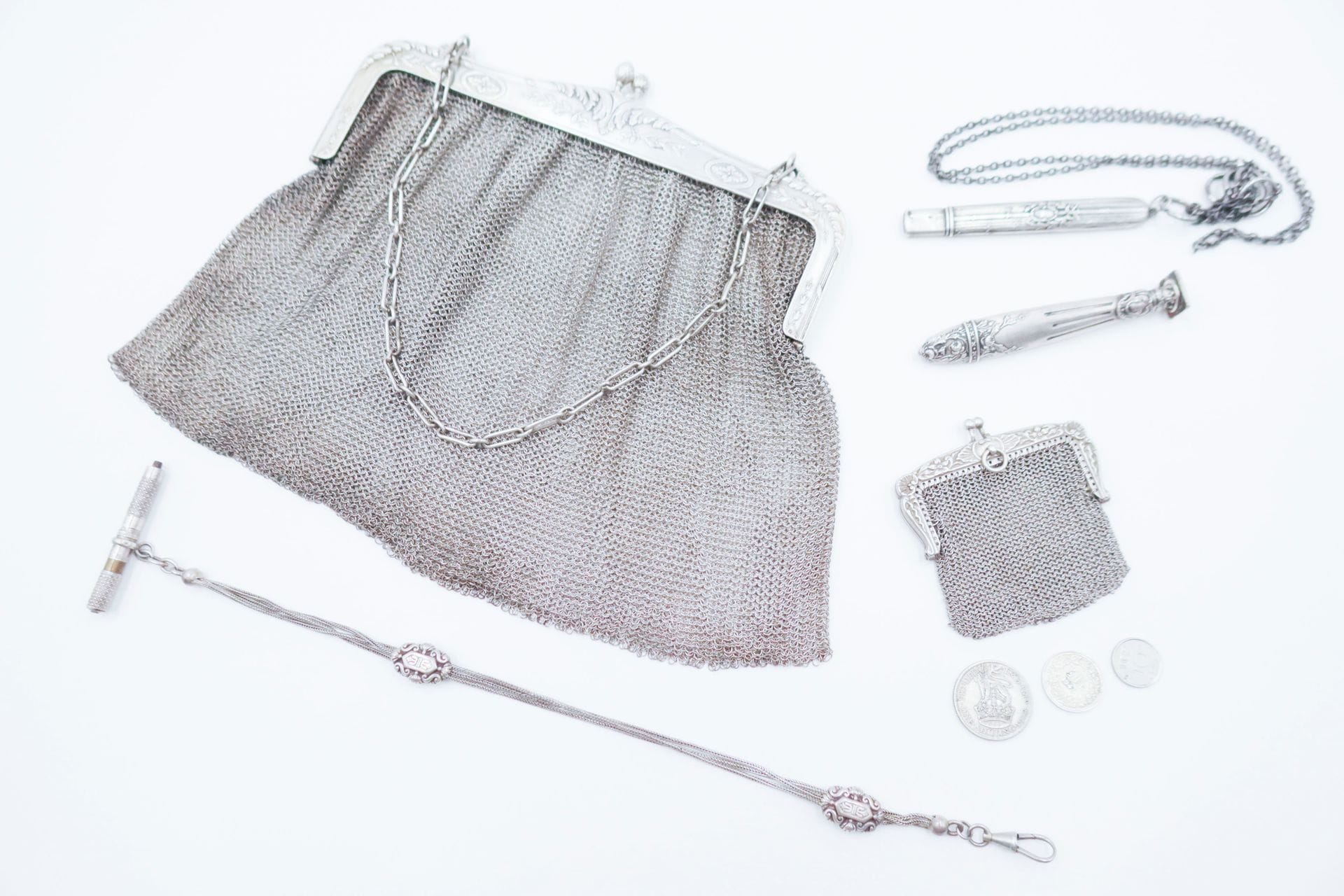 Silver lot including : 1 bag and 1 purse in mesh, 1 seal, 1 lead holder and 1 silver watch chain. Weight : 373,3 g (a metal chain and two coins are attached)