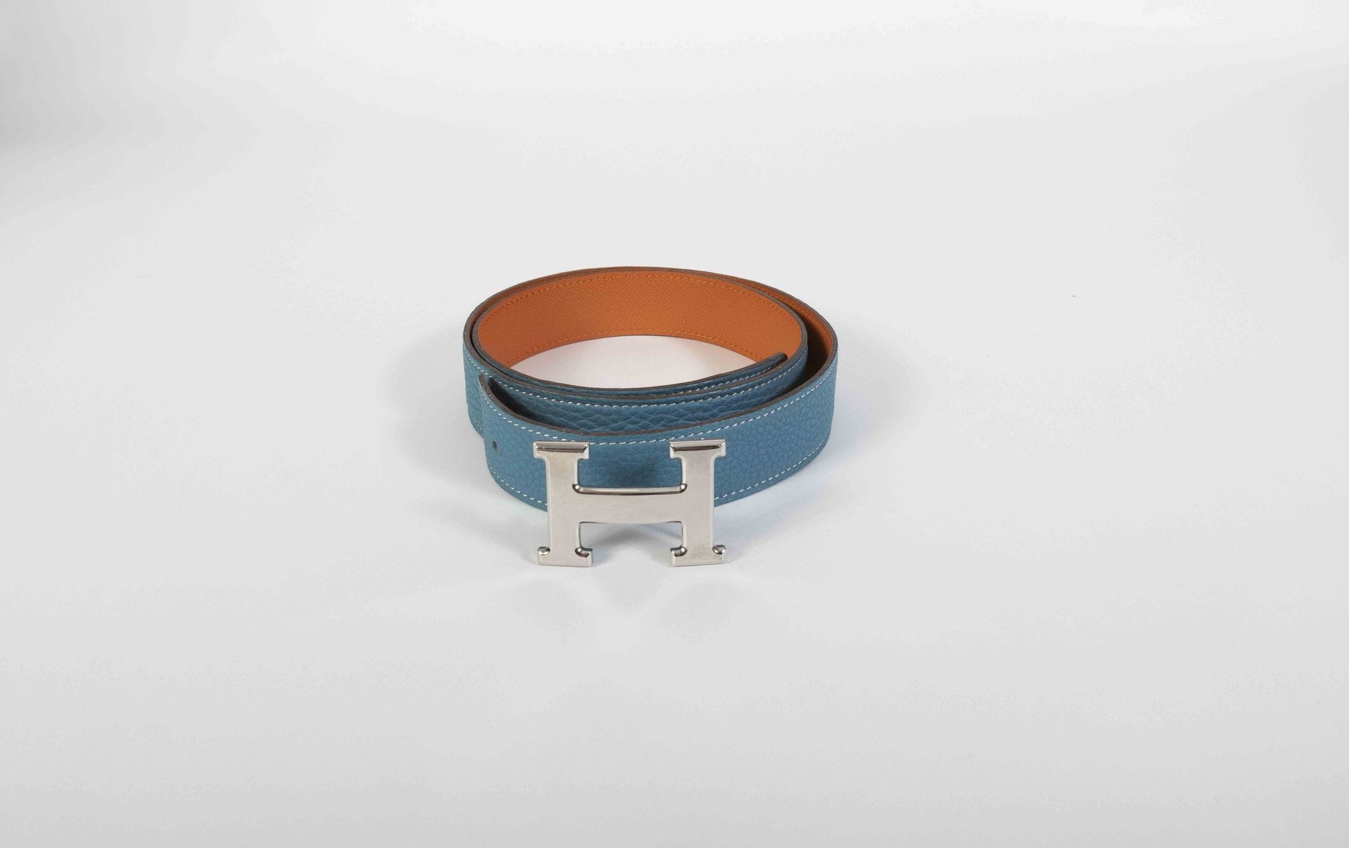 HERMES Paris Made in France. Circa 2005
Ceinture en cuir grainé orange et bleu, boucle de ceinture H en métal argenté, T.90
