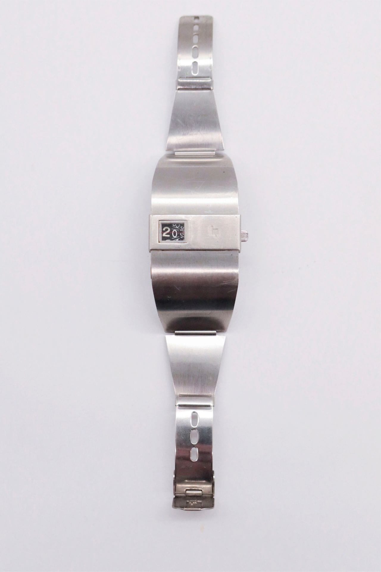 LIP BASCHMAKOFF. Years
70Steel wristwatch with jumping hours. Square case, screwed back. Baguette bezel with opening for display of hours, minutes and seconds linear. Mechanical movement. Integrated stainless steel bracelet with single sliding clasp. 
Signed and numbered 372266.
34 mm in diameter


.