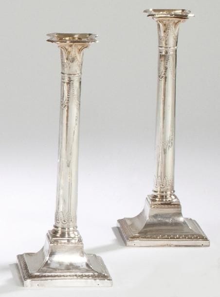 Paire de bougeoirs en métal argenté, la base de forme carrée partiellement décorée d'une moulure de perles, le fût orné de palmes et guirlandes. (Accidents et réparations) Travail étranger. Hauteur: 32,5 cm