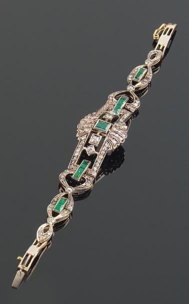 Bracelet articulé en alliage d'or (9 k 375 millièmes) et argent ajouré, serti d'émeraudes calibrées, celle du centre plus importante, et de petits diamants ronds. Longueur: 16 cm Poids brut: 15 g