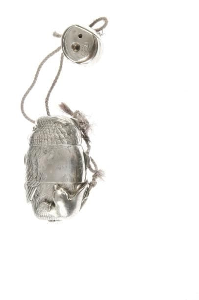 Inro à deux cases en shibuichi en forme de hibou liant un oiseau dans ses serres.  H. 9,6 cm. Netsuke de même matière en forme de poupée daruma. Signé Tomogawa.
